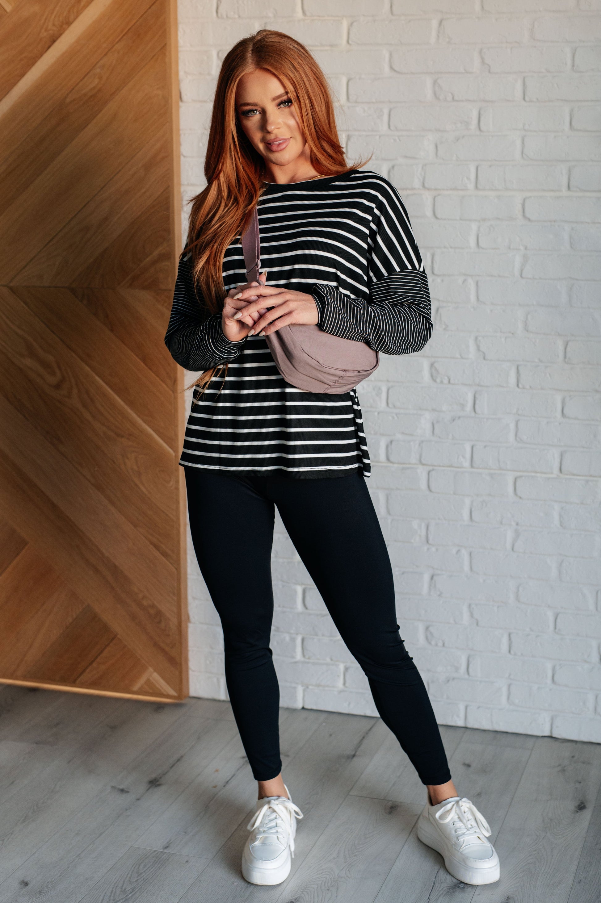 Black and white striped women's top with a round neckline, long drop shoulder sleeves, and banded sleeve cuffs, made from cozy micro ribbed knit fabric.