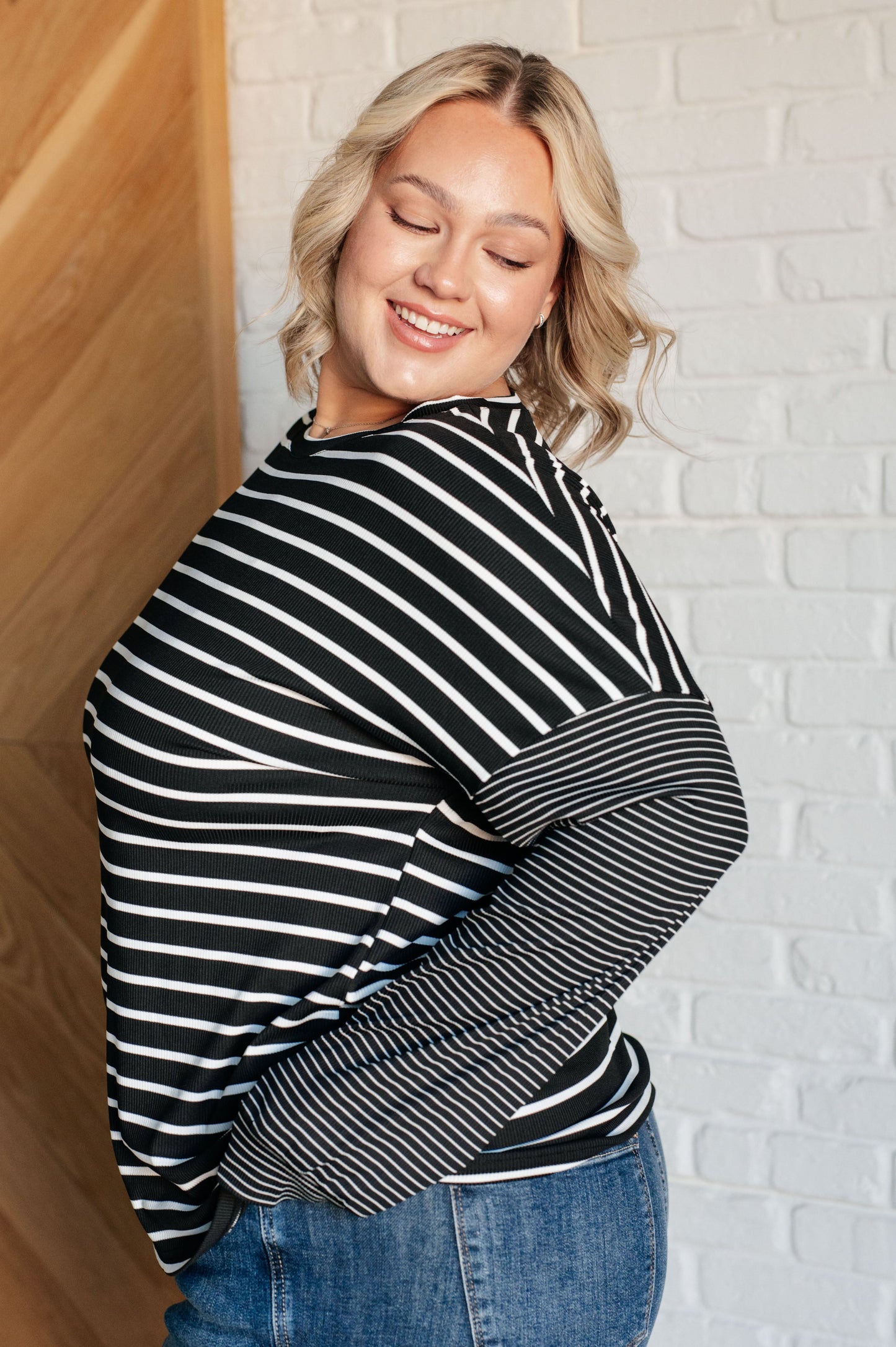 Black and white striped women's top with a round neckline, long drop shoulder sleeves, and banded sleeve cuffs, made from cozy micro ribbed knit fabric.