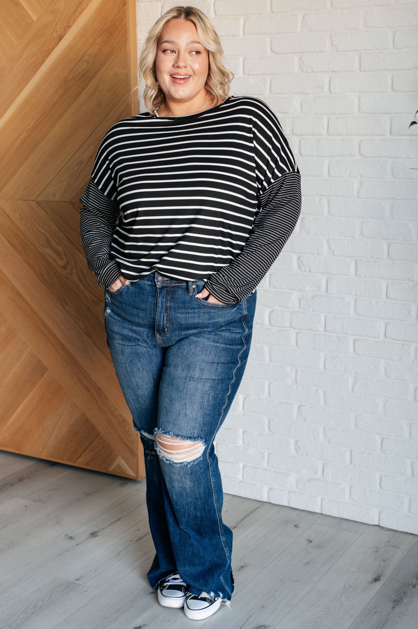 Black and white striped women's top with a round neckline, long drop shoulder sleeves, and banded sleeve cuffs, made from cozy micro ribbed knit fabric.