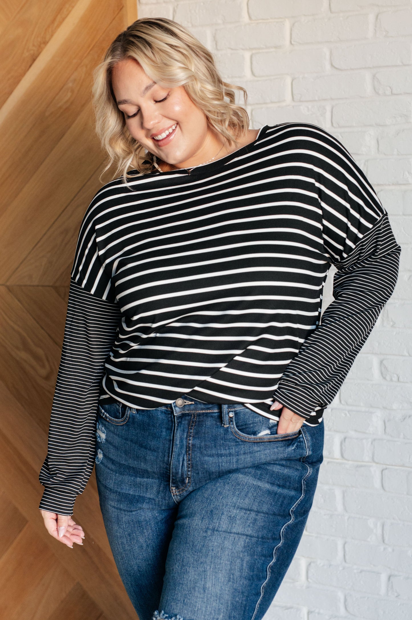 Black and white striped women's top with a round neckline, long drop shoulder sleeves, and banded sleeve cuffs, made from cozy micro ribbed knit fabric.