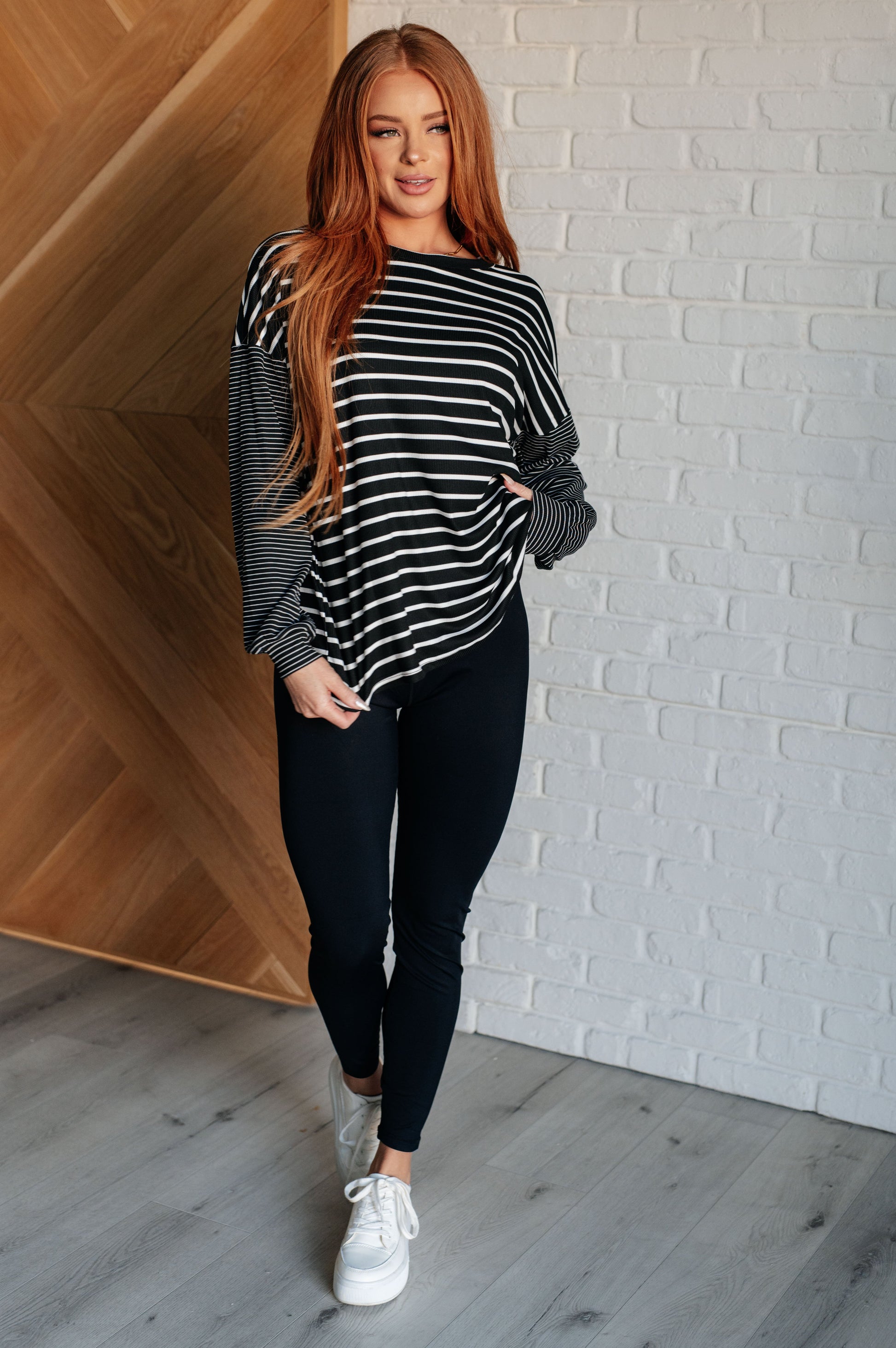 Black and white striped women's top with a round neckline, long drop shoulder sleeves, and banded sleeve cuffs, made from cozy micro ribbed knit fabric.