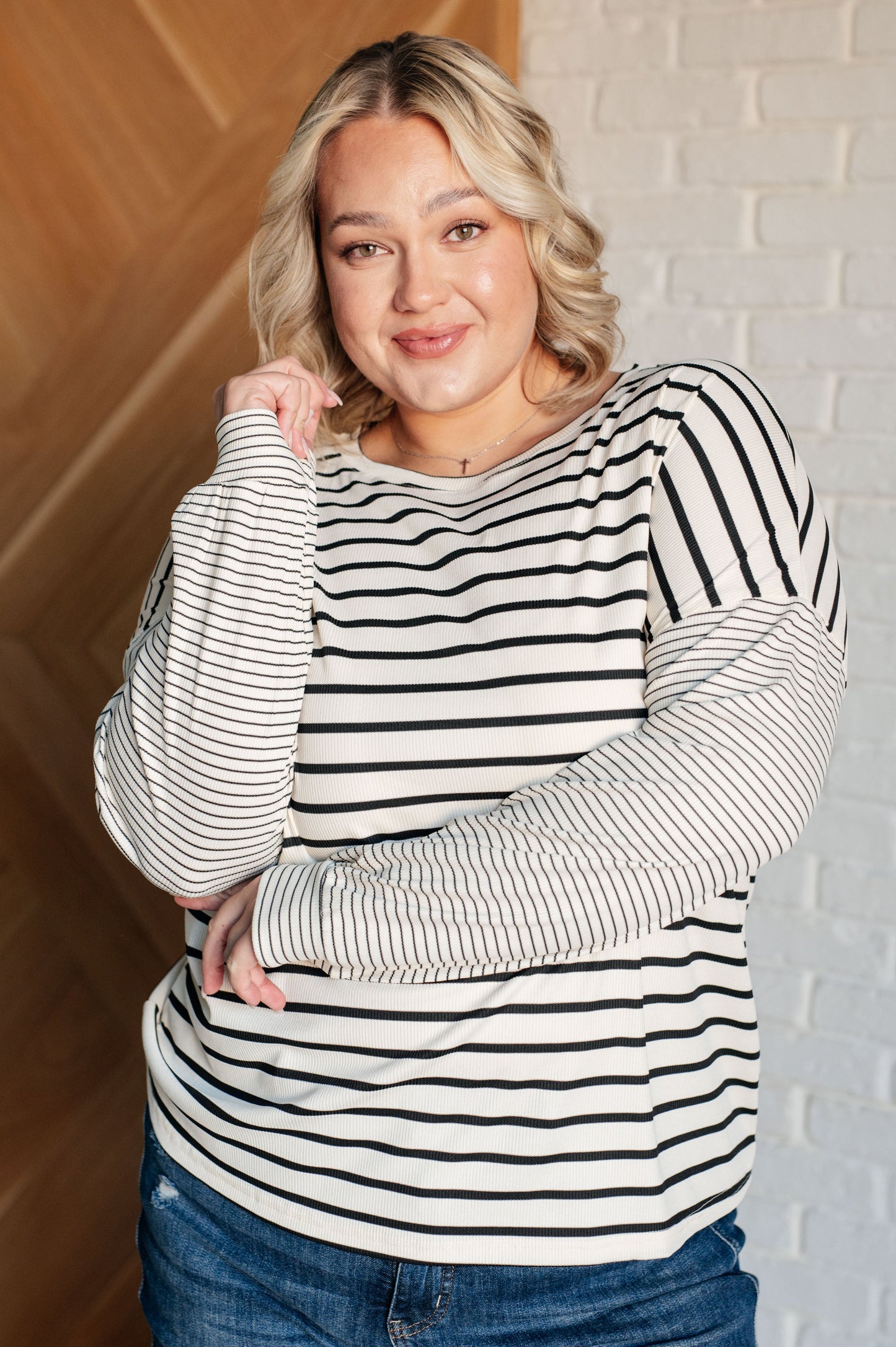 Ivory and black striped women's top with a round neckline, long drop shoulder sleeves, and banded sleeve cuffs, made from cozy micro ribbed knit fabric.