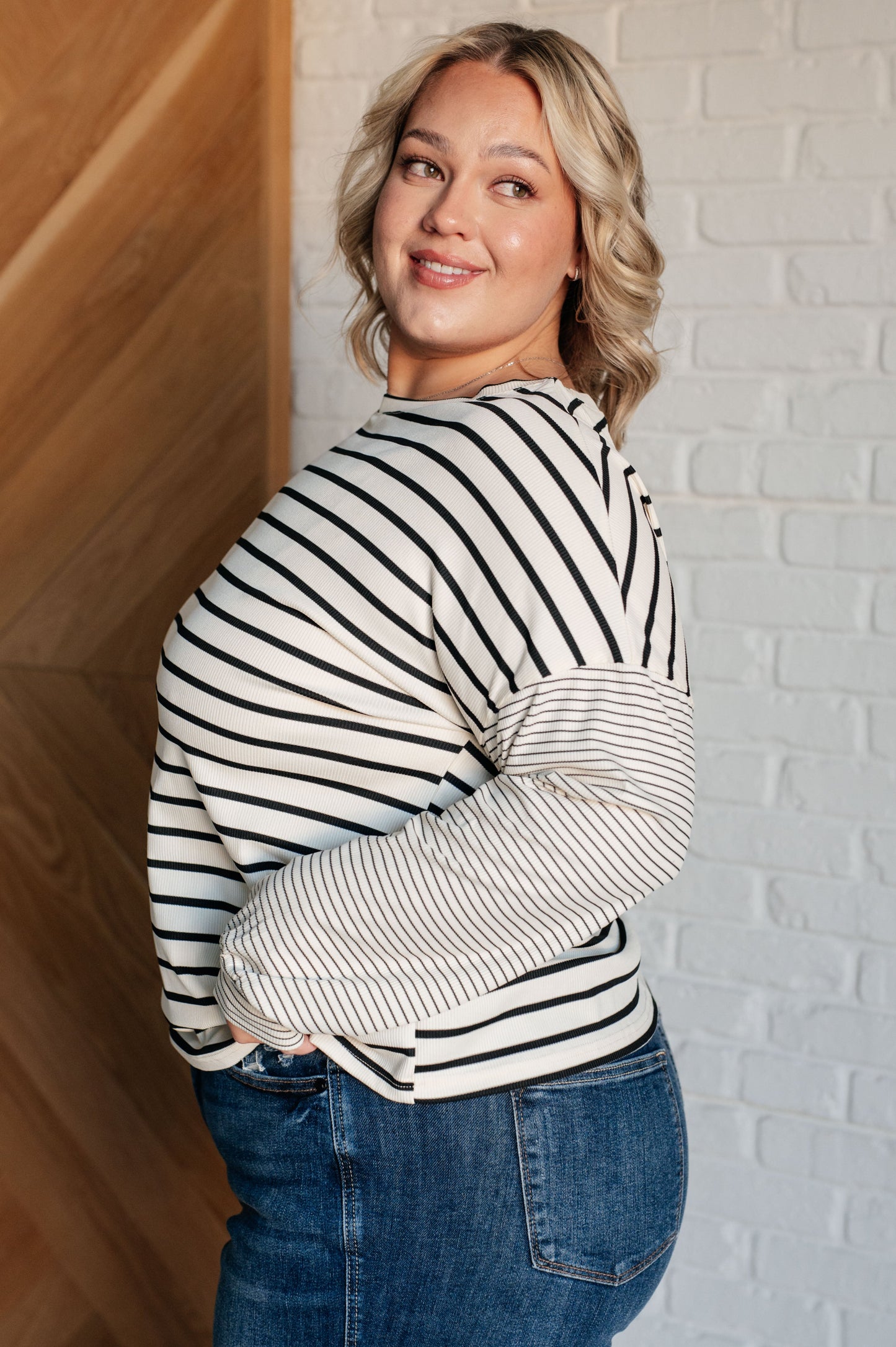 Ivory and black striped women's top with a round neckline, long drop shoulder sleeves, and banded sleeve cuffs, made from cozy micro ribbed knit fabric.