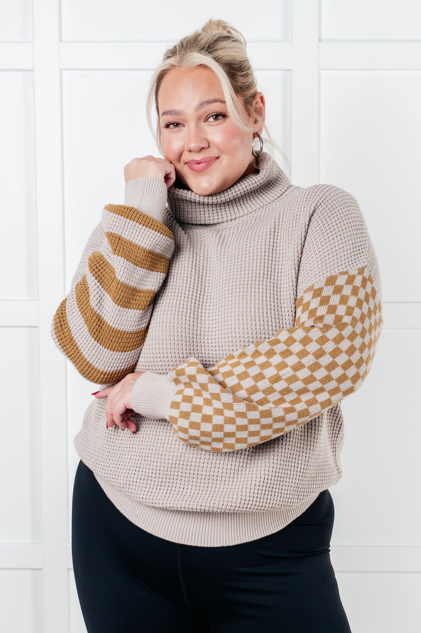 Alt text: "Suzi Patchwork Waffle Knit Sweater with a soft waffle knit texture, turtle neckline, drop shoulder design, and banded ribbed details, featuring check and striped patterns."