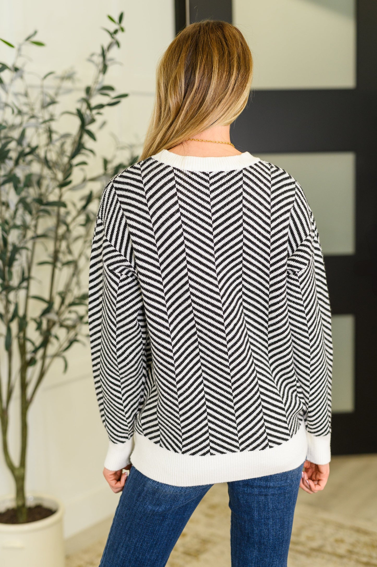 Back view of Selene Chevron Sweater in black with chevron knit texture and ribbed banded hemline.