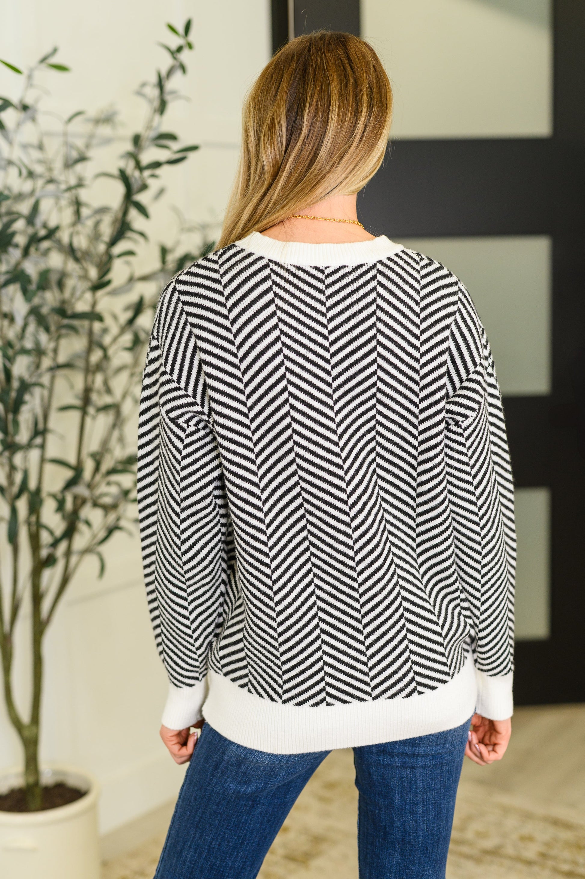 Back view of Selene Chevron Sweater in black with chevron knit texture and ribbed banded hemline.
