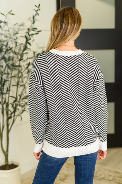 Back view of Selene Chevron Sweater in black with chevron knit texture and ribbed banded hemline.