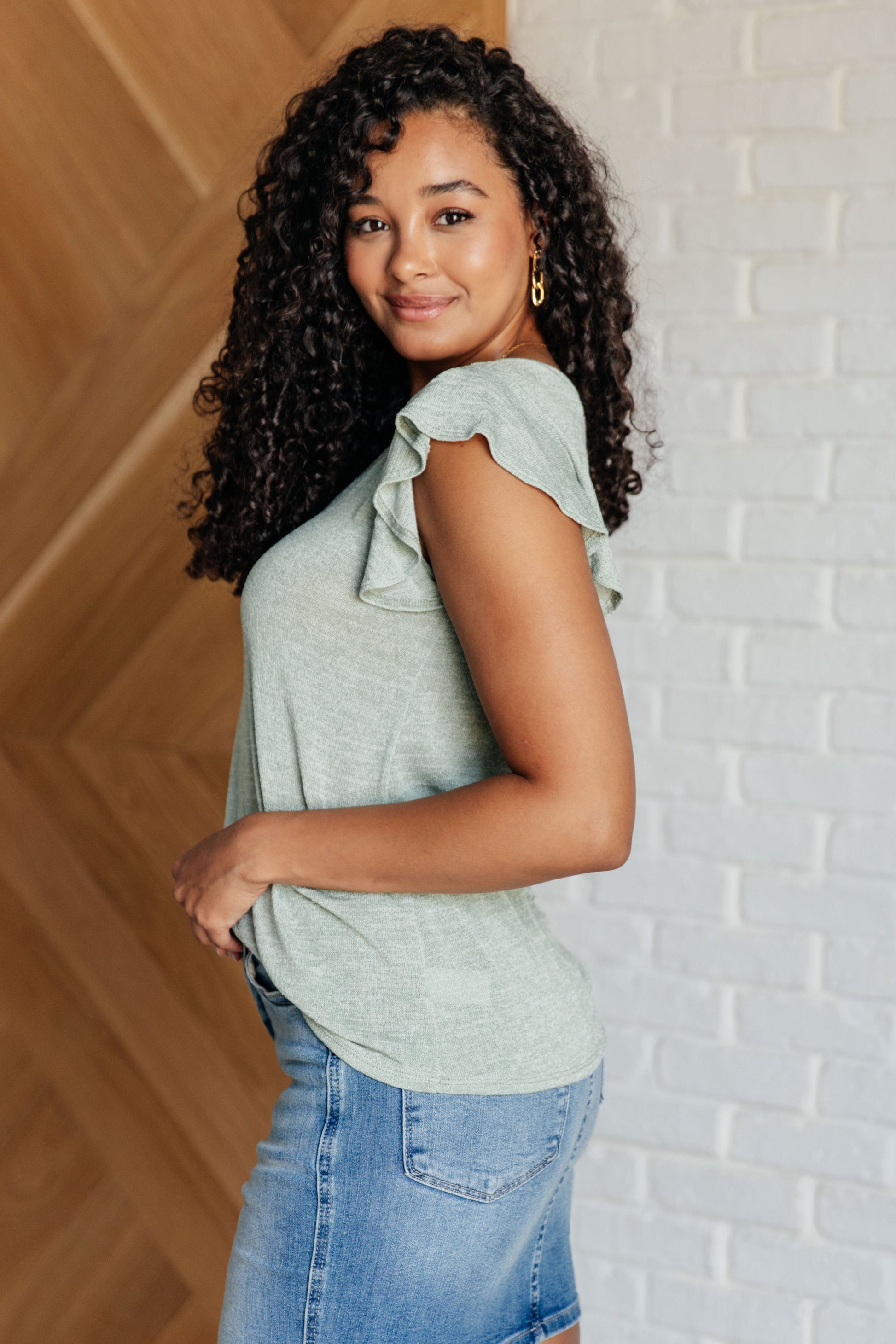 Side angle of Teresa Flutter Sleeve Top in sage, showing relaxed fit and soft flutter sleeve detail