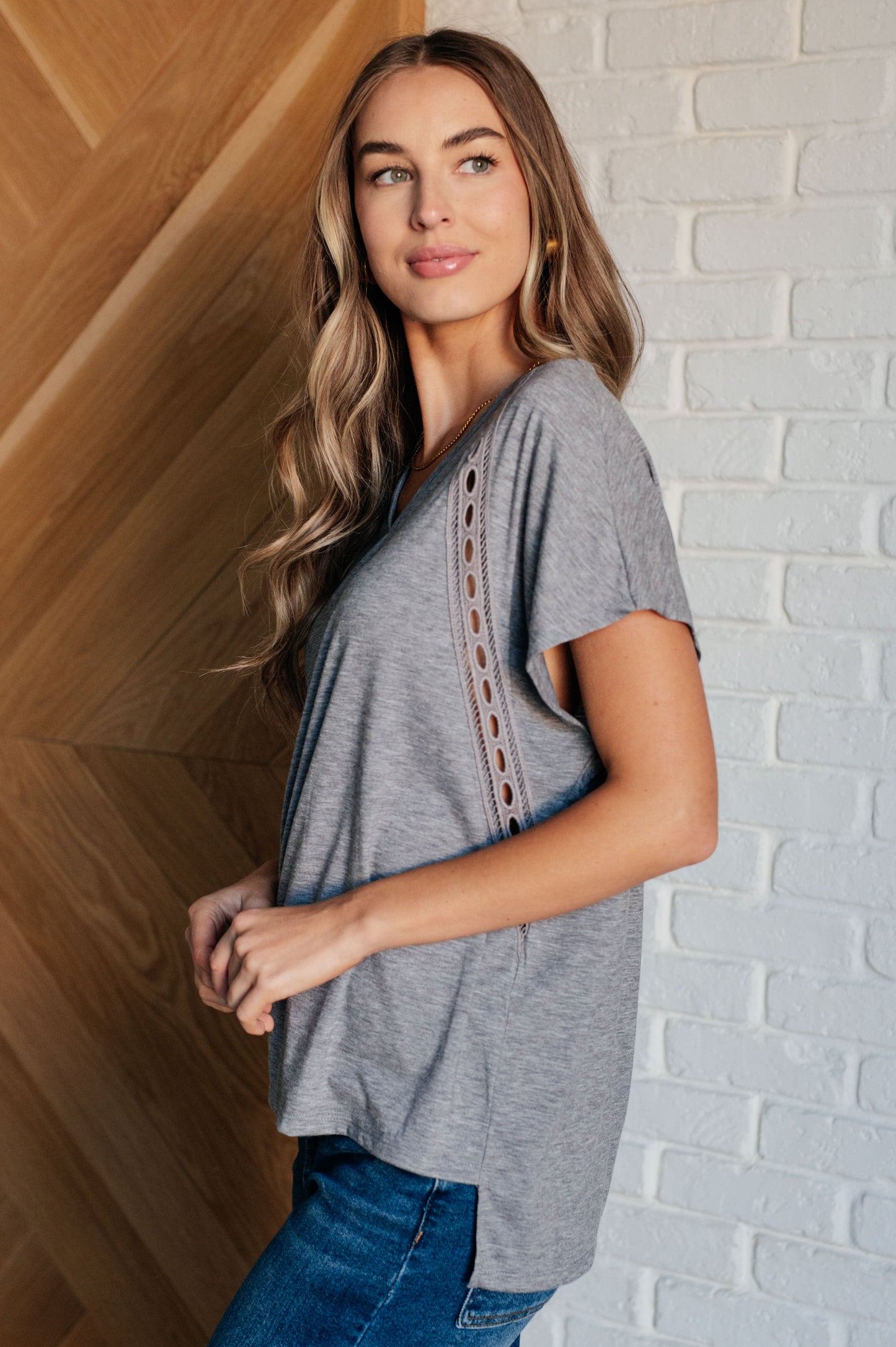 Siana Eyelet Trim Top in gray with V-neckline, batwing sleeves, eyelet trim detailing, and a stepped hemline.