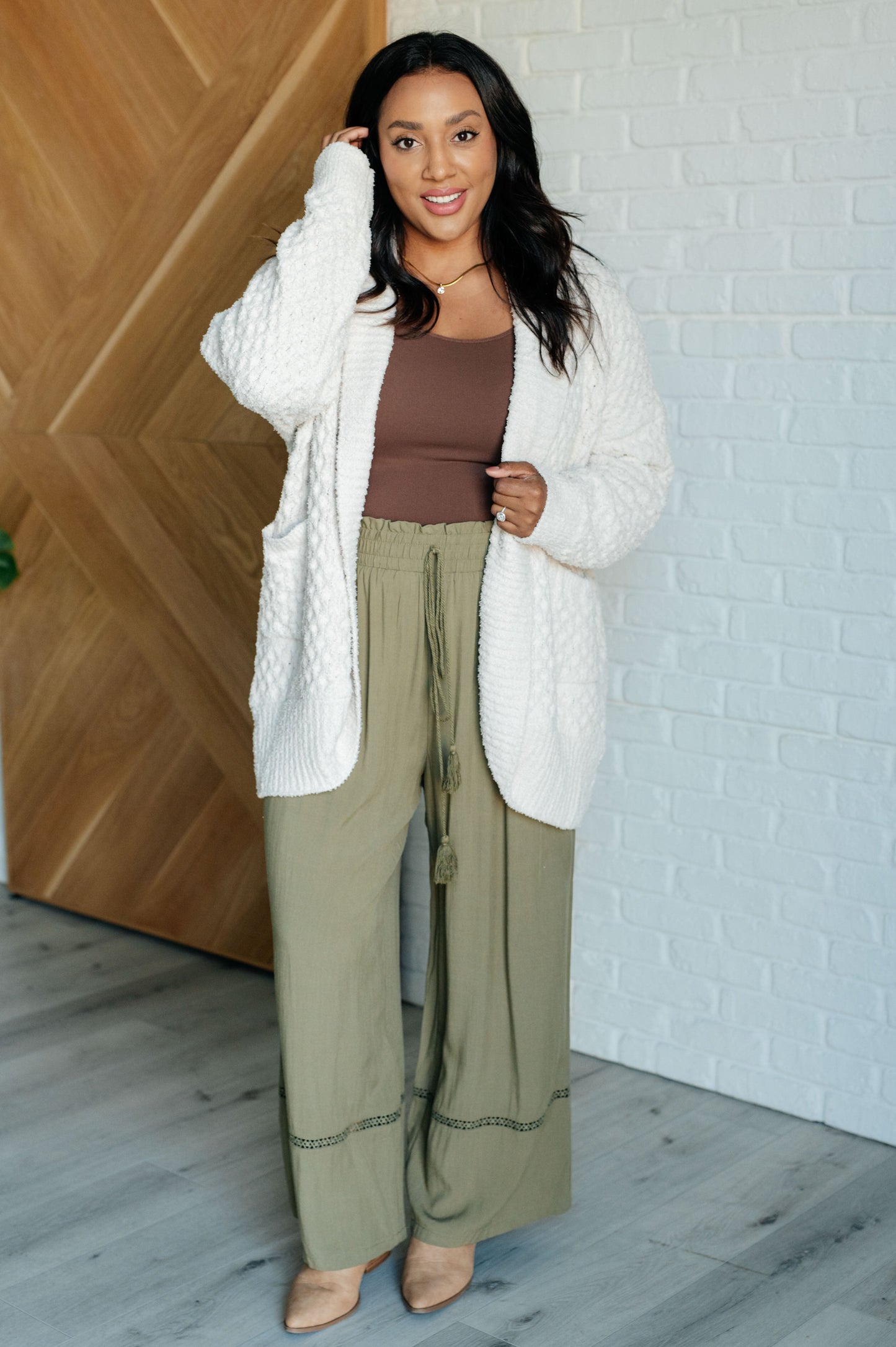 Women's off-white cardigan made of super soft sweater knit fabric. Features a shawl collar, long sleeves with dropped shoulders, ribbed cuffs and hem, and pockets. Open front with a longline silhouette.