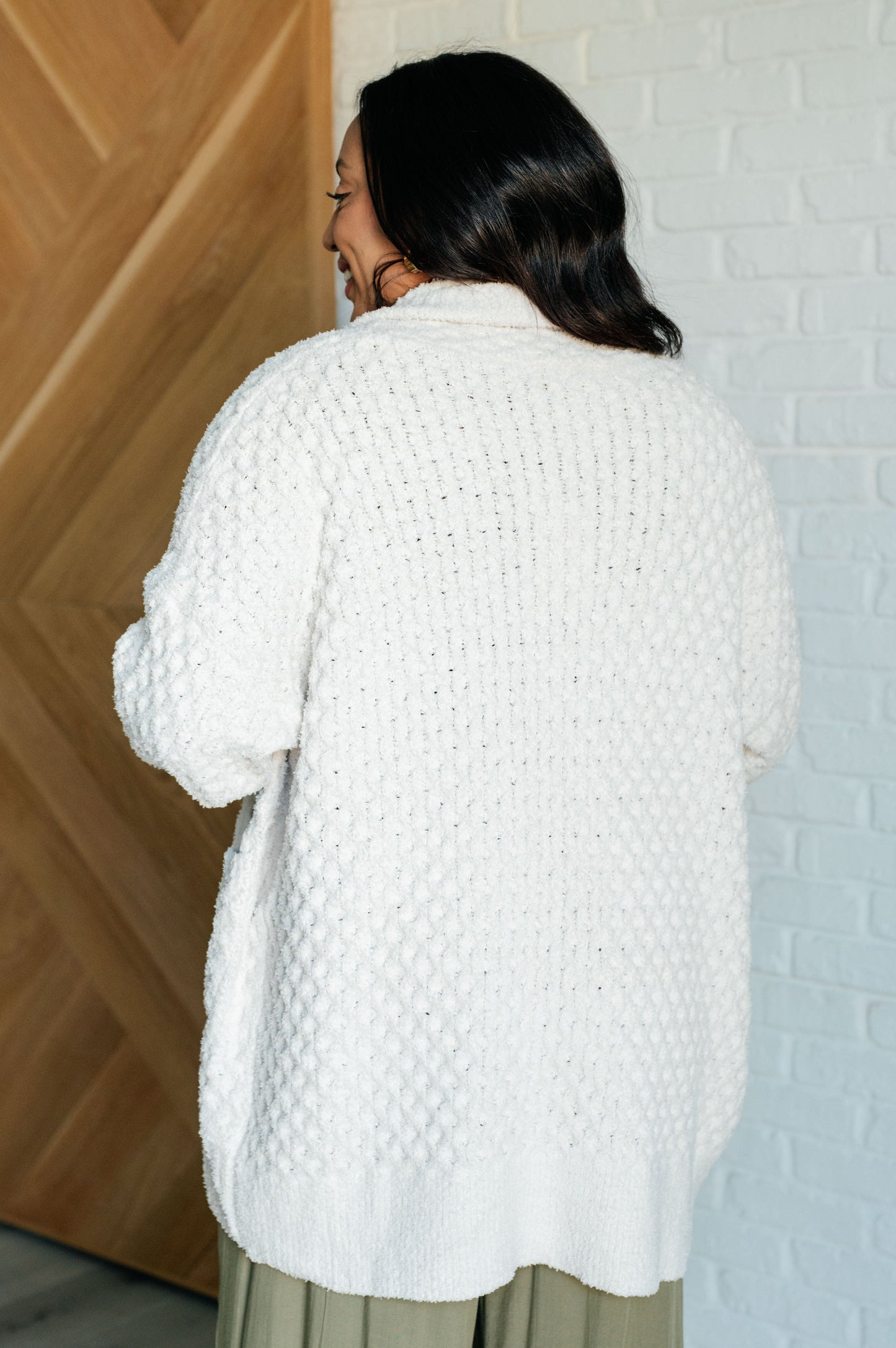 Women's off-white cardigan made of super soft sweater knit fabric. Features a shawl collar, long sleeves with dropped shoulders, ribbed cuffs and hem, and pockets. Open front with a longline silhouette.