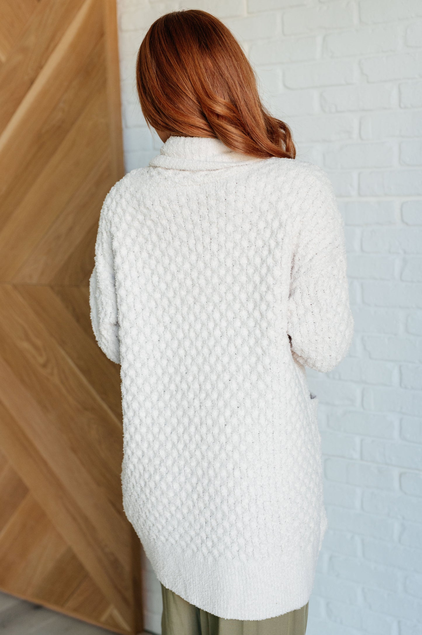 Women's off-white cardigan made of super soft sweater knit fabric. Features a shawl collar, long sleeves with dropped shoulders, ribbed cuffs and hem, and pockets. Open front with a longline silhouette.