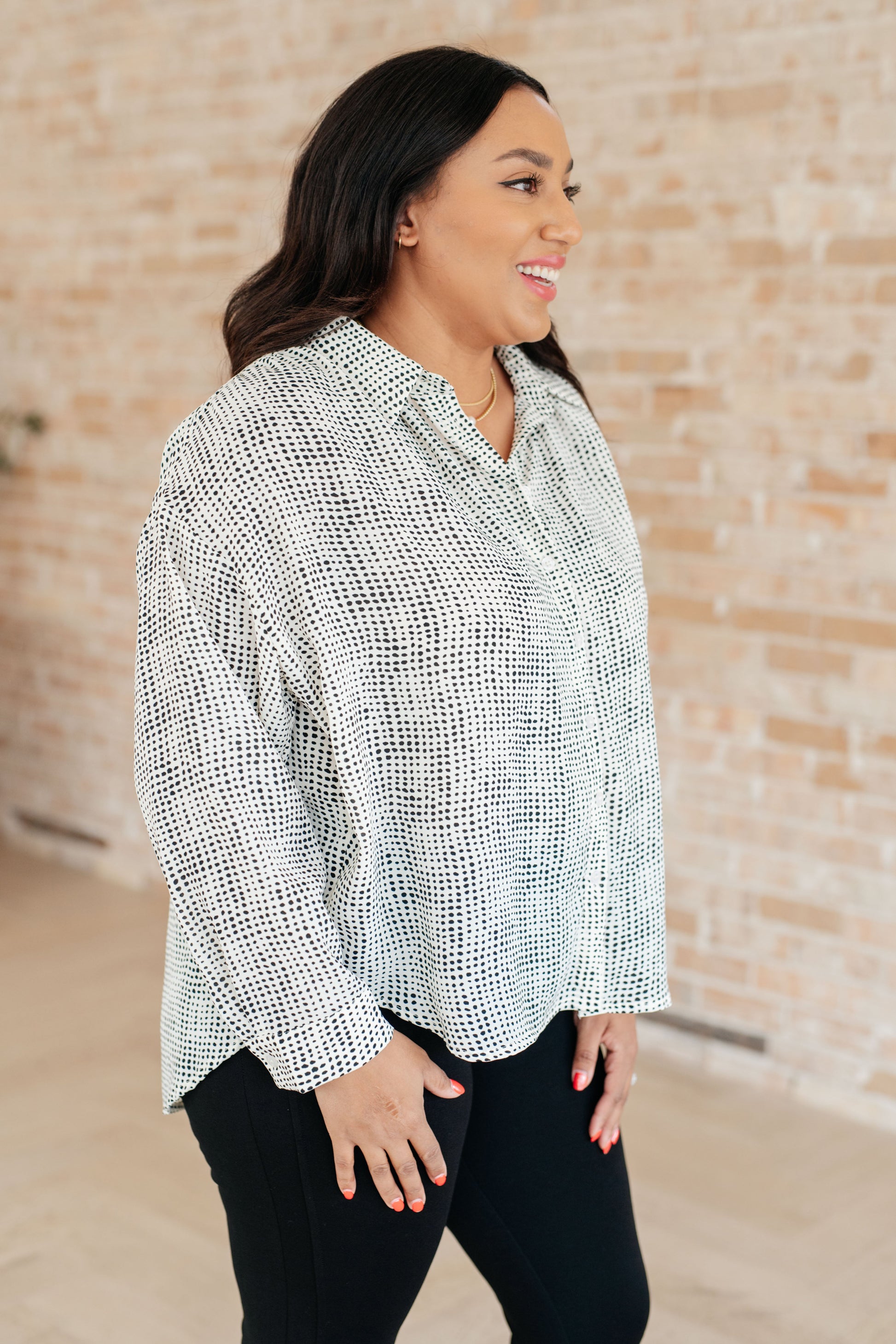 Women's spotted button-up top with dolman sleeves, collared neckline, and high-low hem.