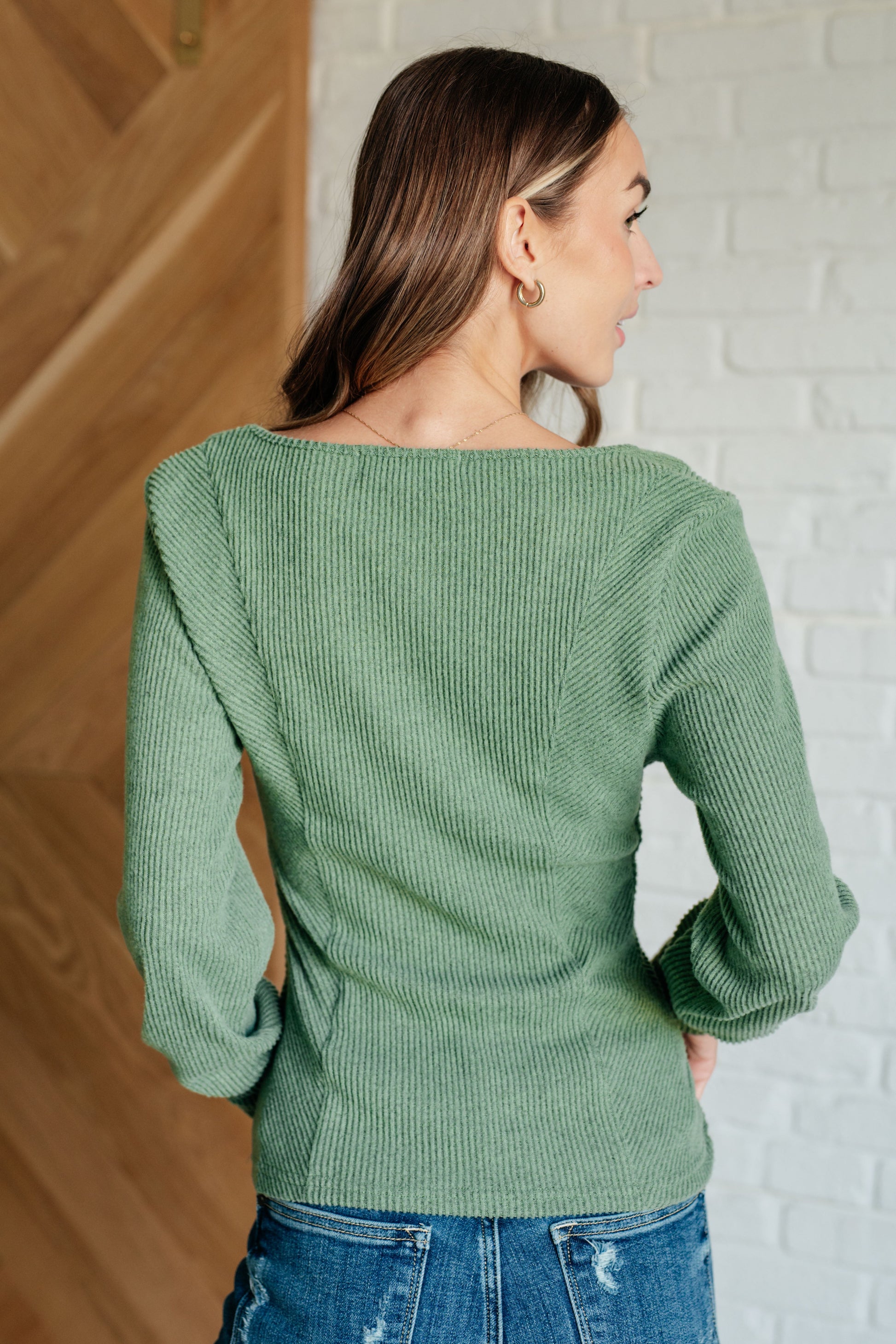 Sage ribbed knit top with a scoop neckline, long sleeves featuring exaggerated cuffs, and a form-fitting silhouette.