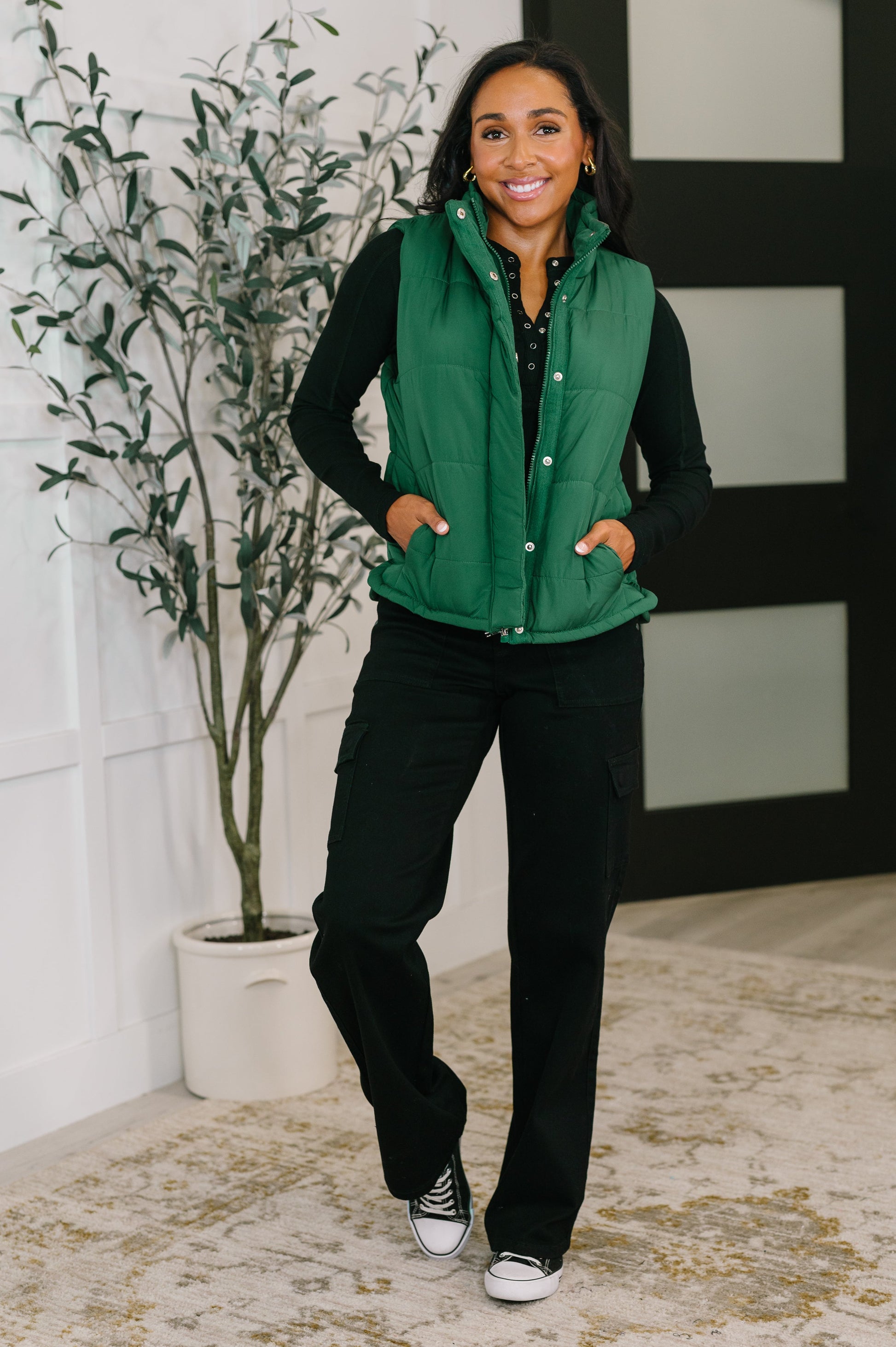 Model wearing Izabella Puffer Vest in hunter green styled with black top and pants.
