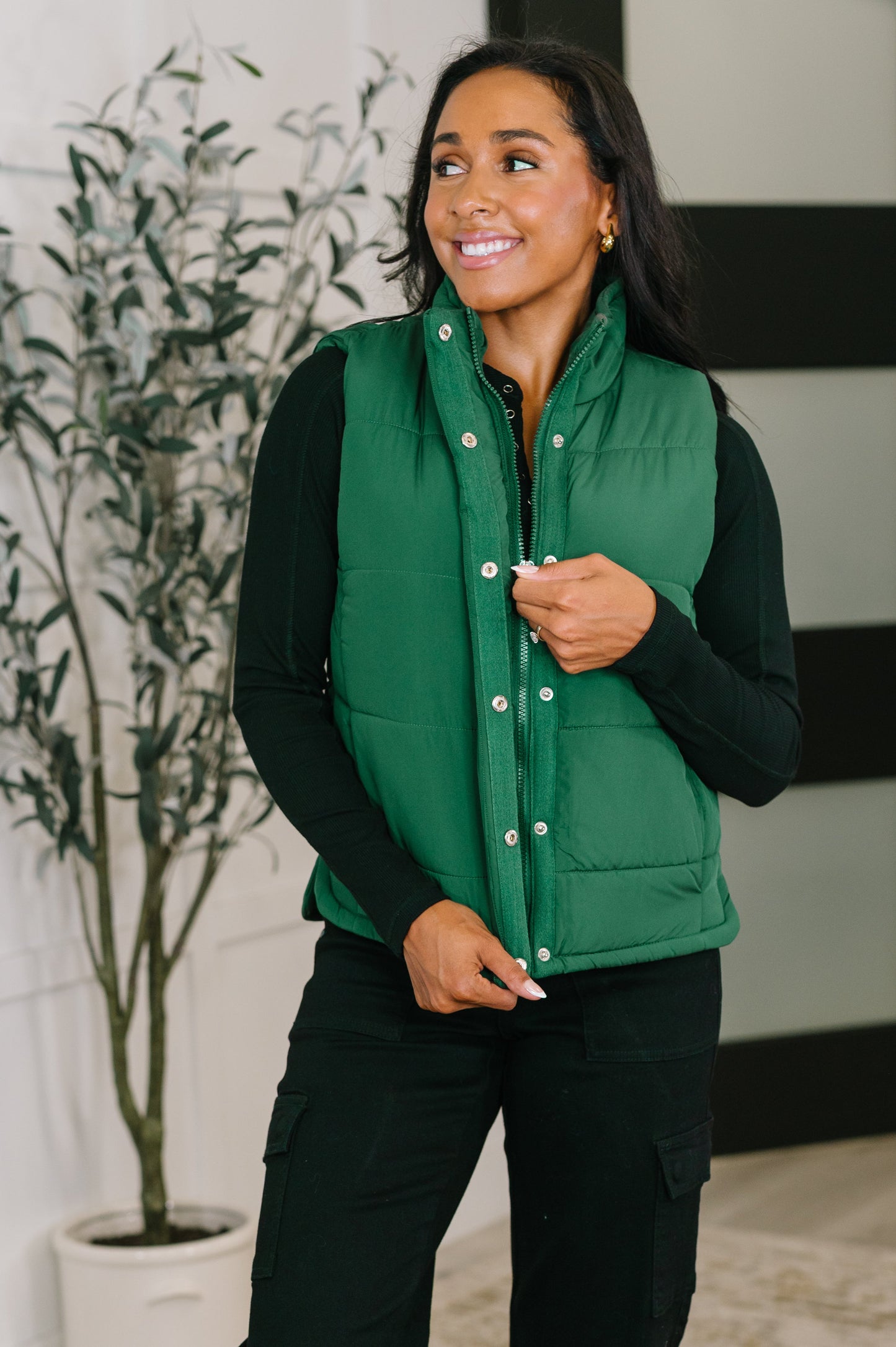 Model wearing Izabella Puffer Vest in hunter green, front view with high neck and snap buttons.