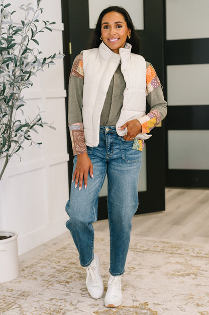 Model wearing Izabella Puffer Vest in sand beige with jeans and neutral long sleeve top.