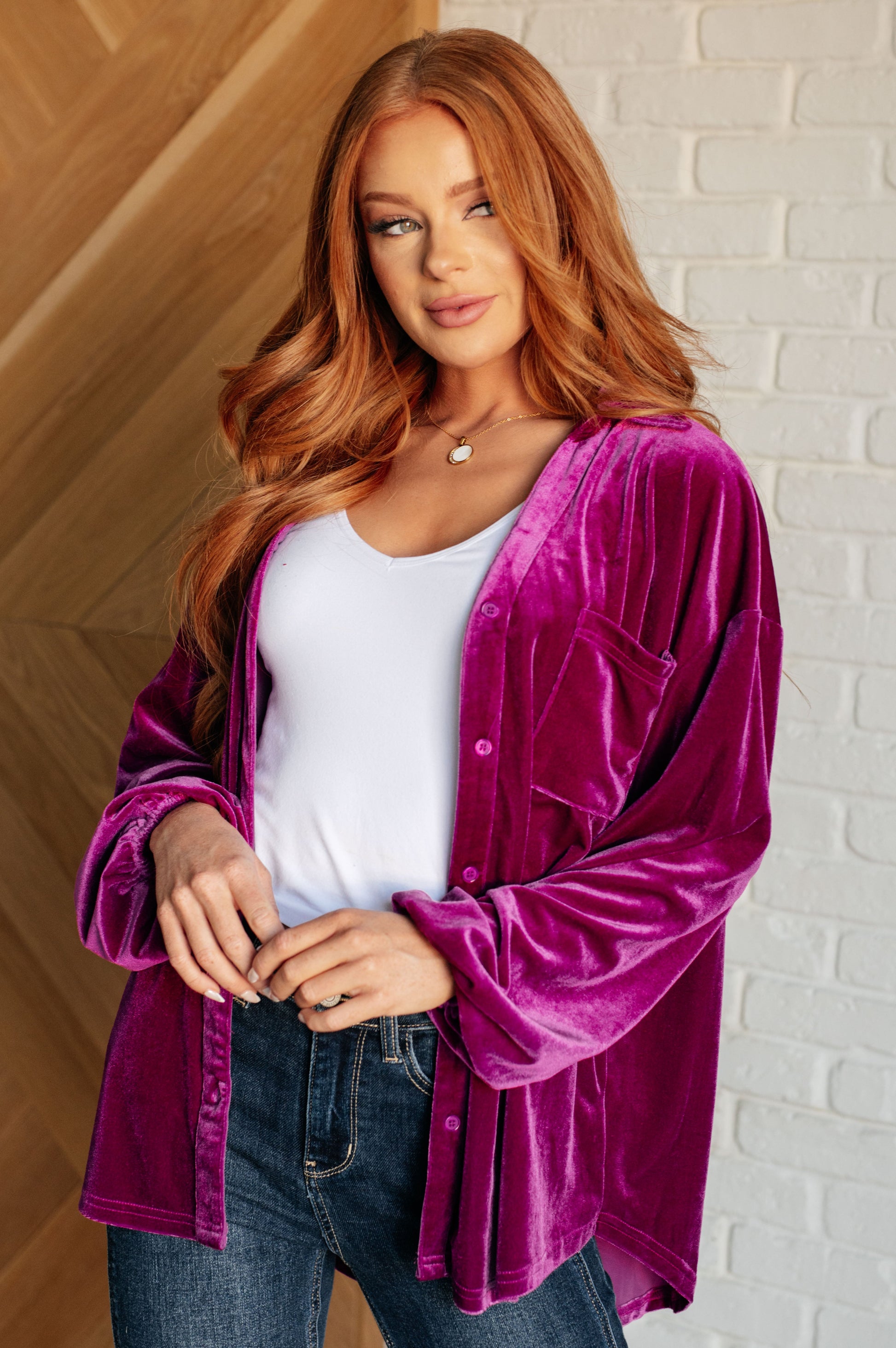 Purple velvet balloon sleeve top with a collared neckline and drop shoulder. Features long balloon sleeves with elastic cuffs, front button closures, a scooped hemline, a patch pocket, and a back gathered detail.