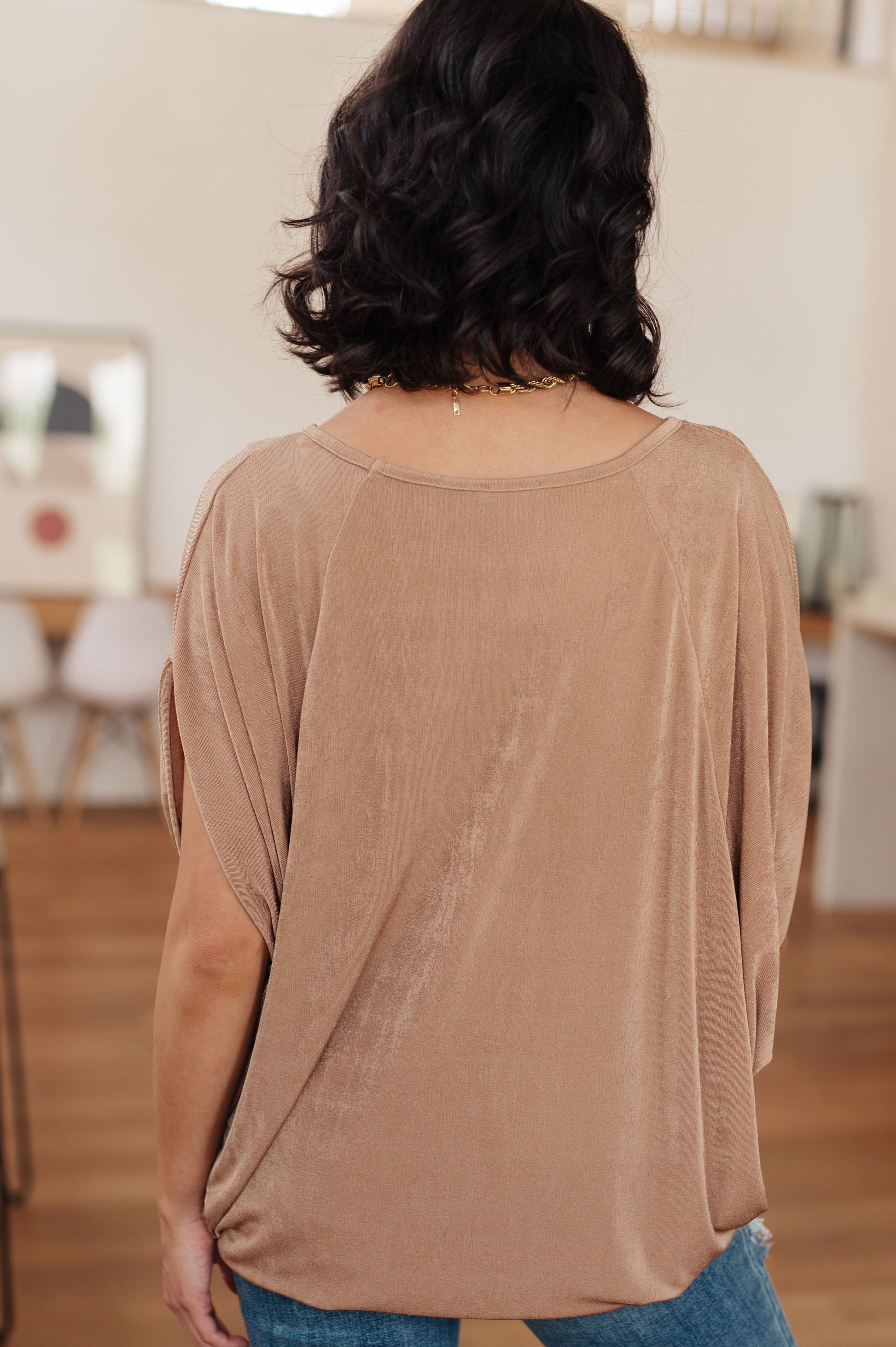 Beige V-neck top made from shimmering bulgari fabric, featuring draped batwing sleeves.