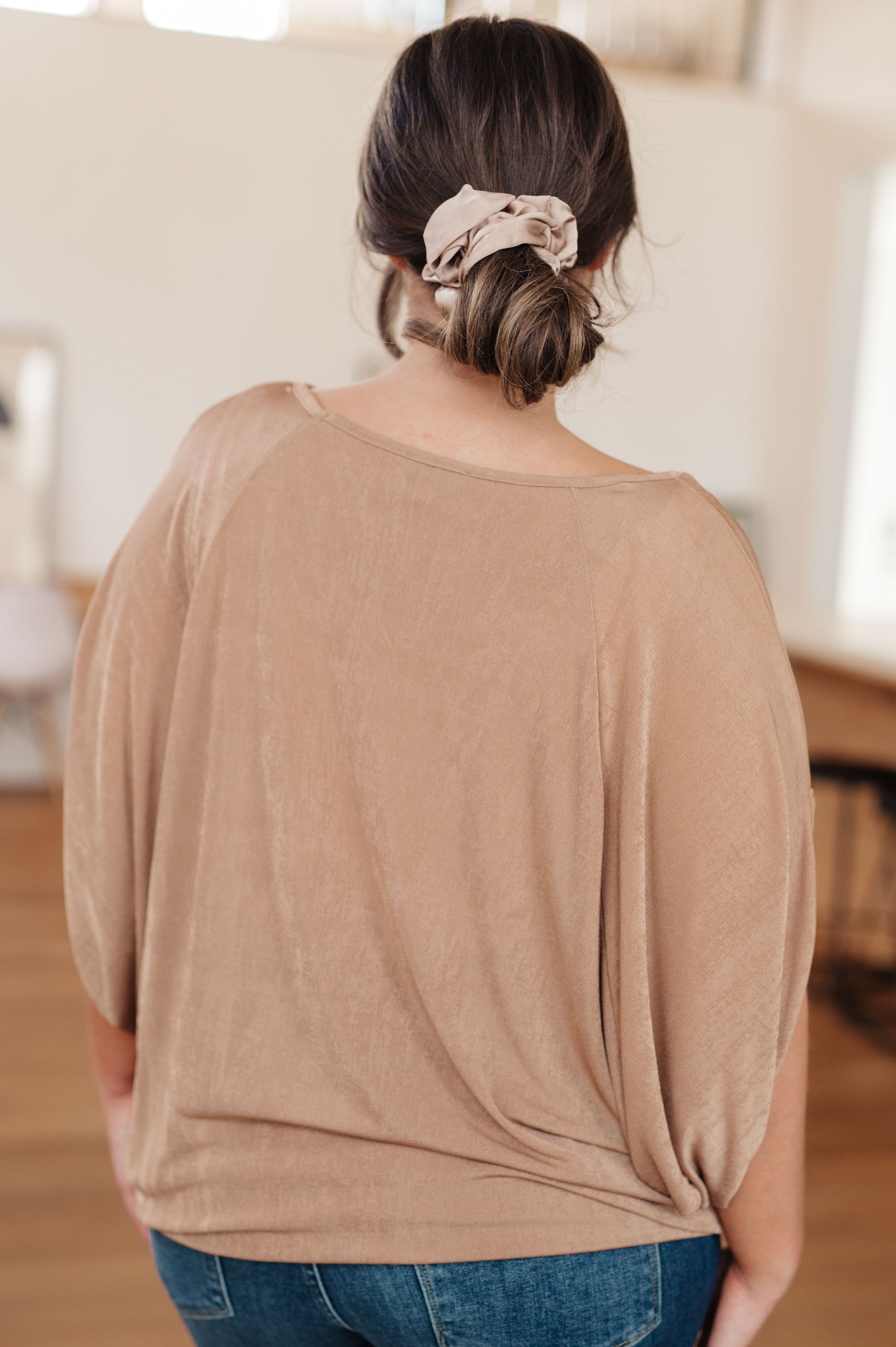 Beige V-neck top made from shimmering bulgari fabric, featuring draped batwing sleeves.