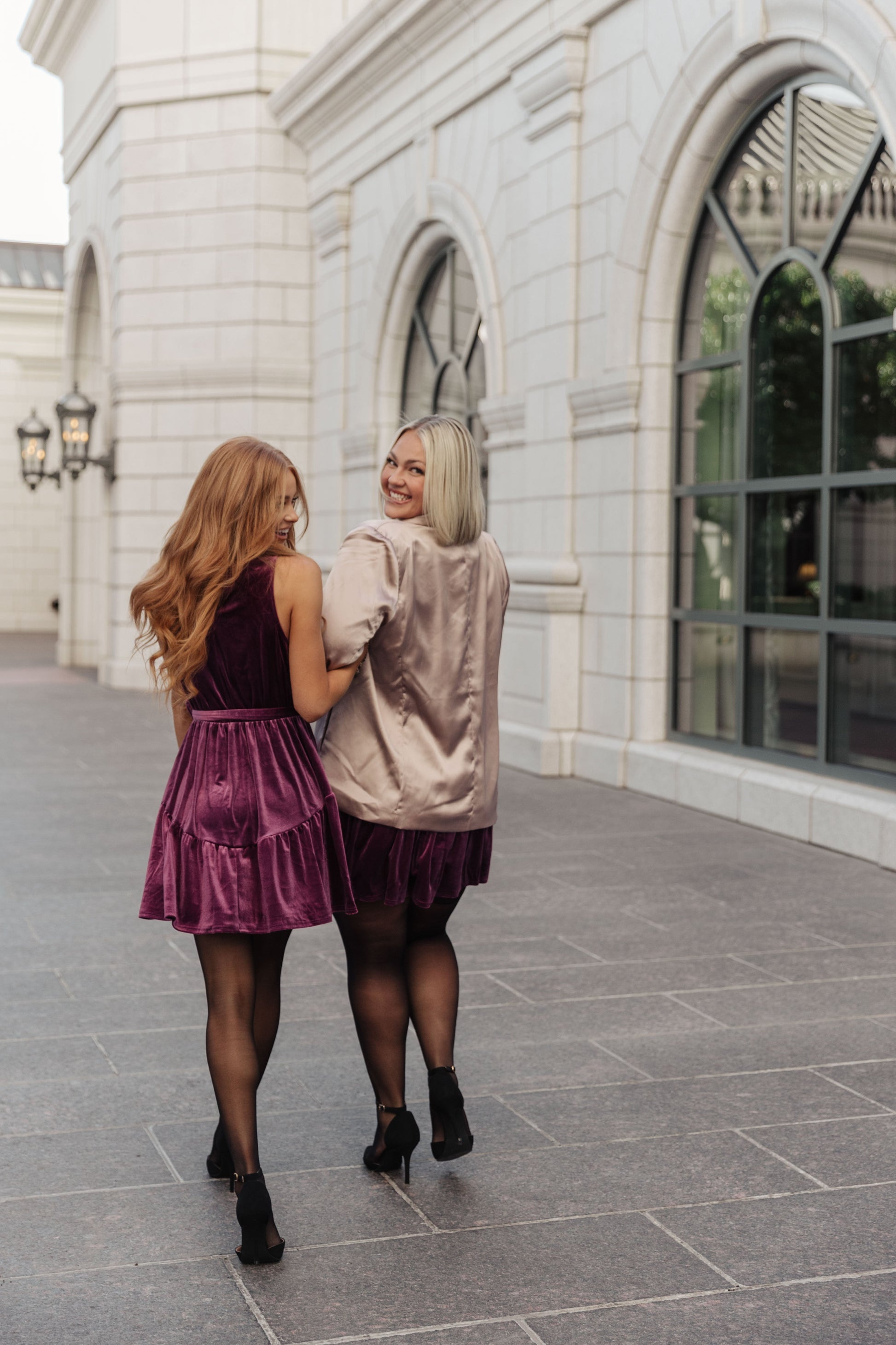 Purple velvet sleeveless dress with a mock neckline, keyhole button closure, and cased elastic waistband. Features a removable self-tie belt, ruffled hem, and is fully lined.