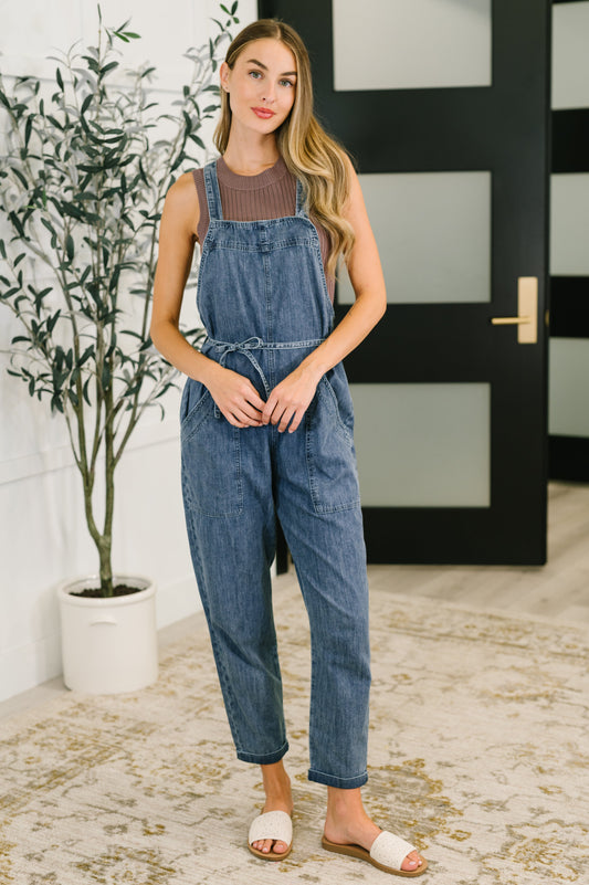 Model wearing Tobin Waist Tie Overalls in dark wash chambray with square neckline and relaxed fit.