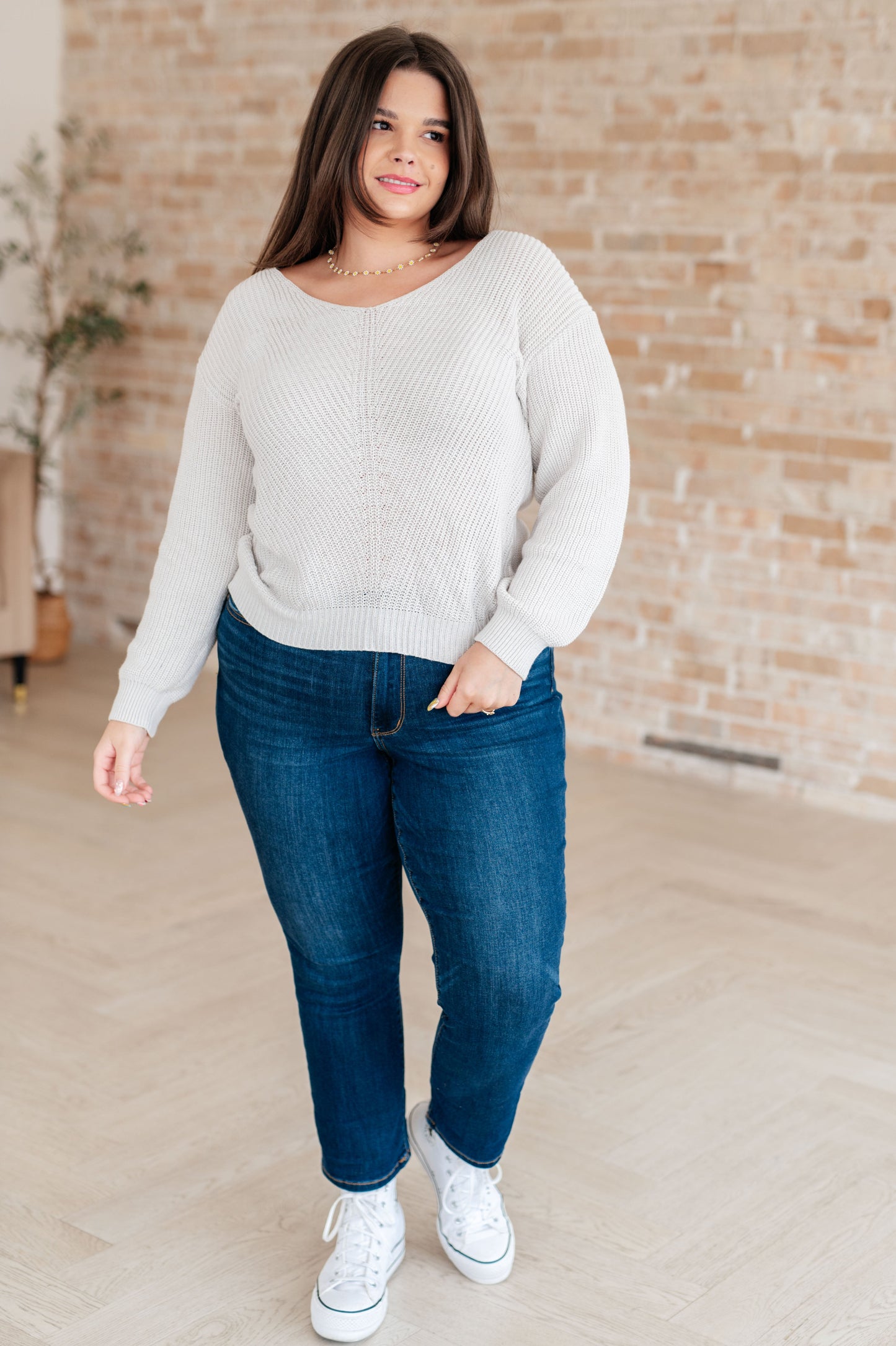 Women's light gray slim fit sweater with a V-neckline and long sleeves, made from lightweight sweater knit fabric.