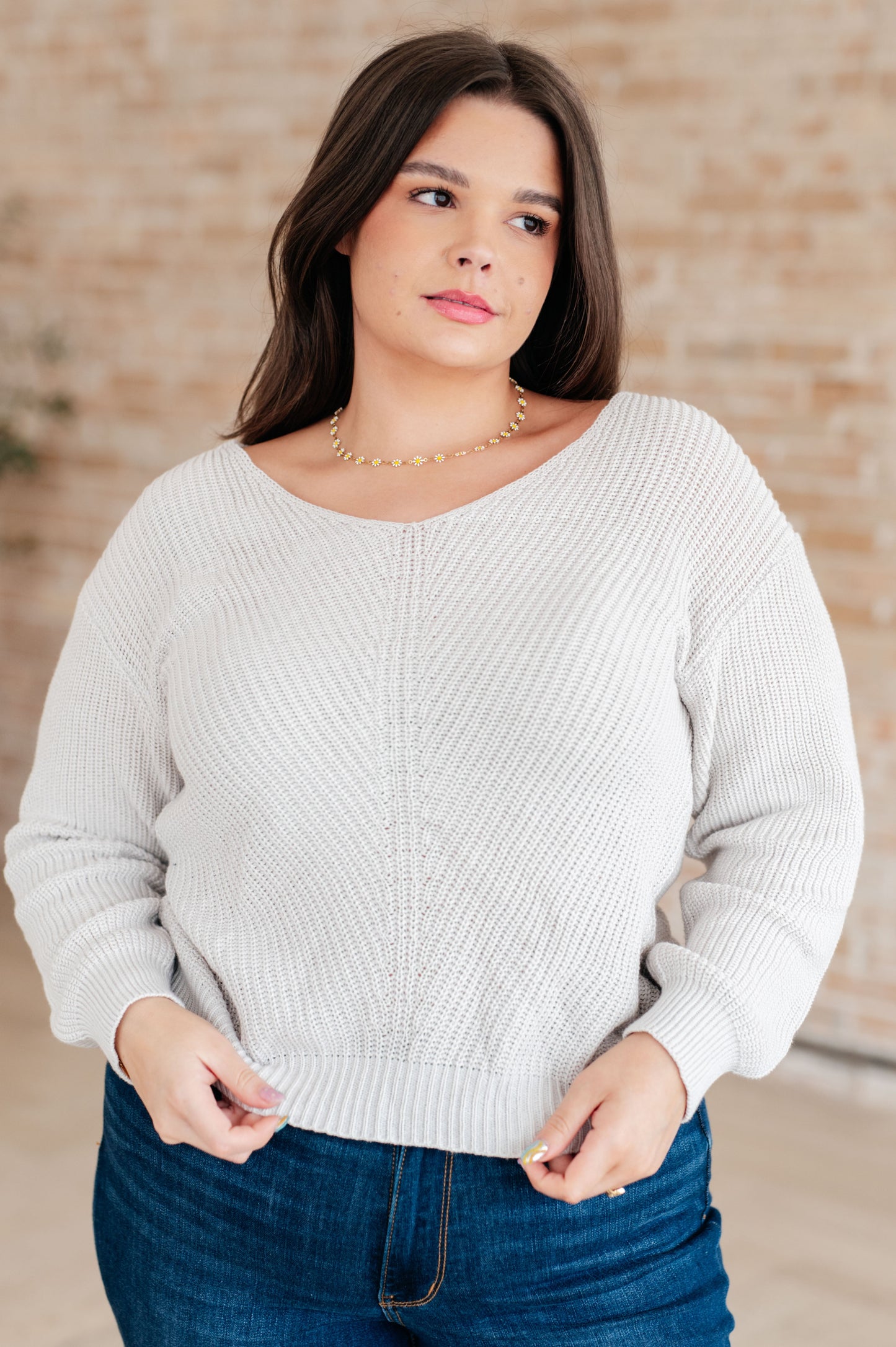 Women's light gray slim fit sweater with a V-neckline and long sleeves, made from lightweight sweater knit fabric.