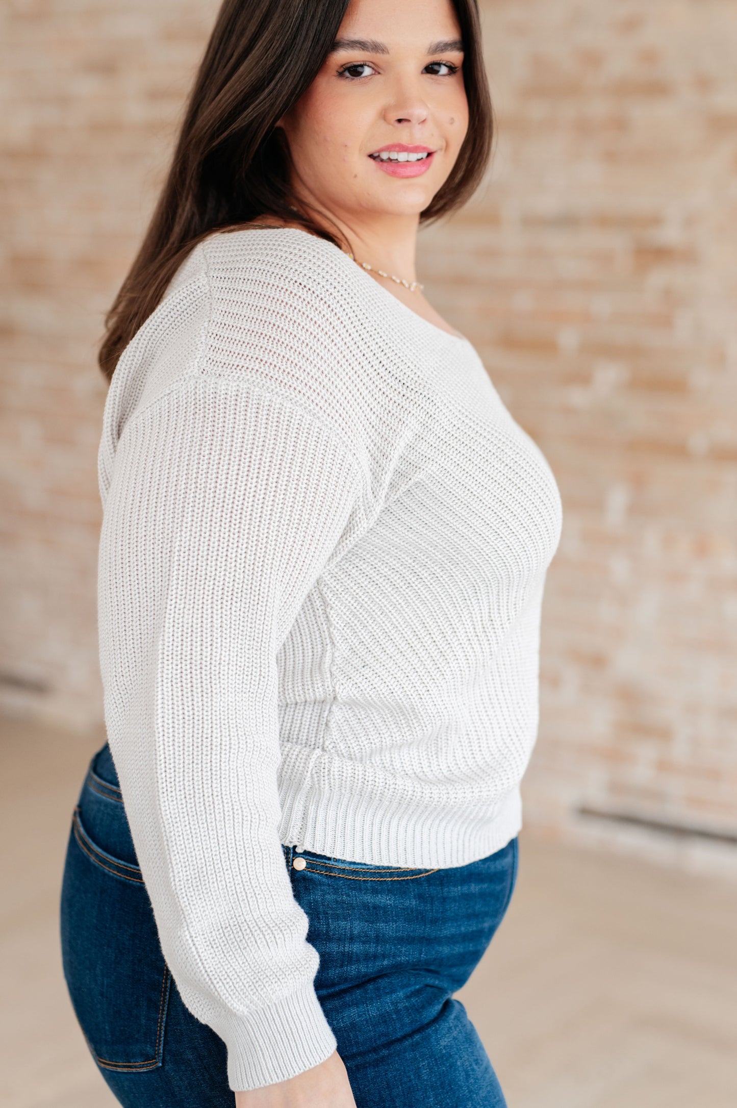 Women's light gray slim fit sweater with a V-neckline and long sleeves, made from lightweight sweater knit fabric.