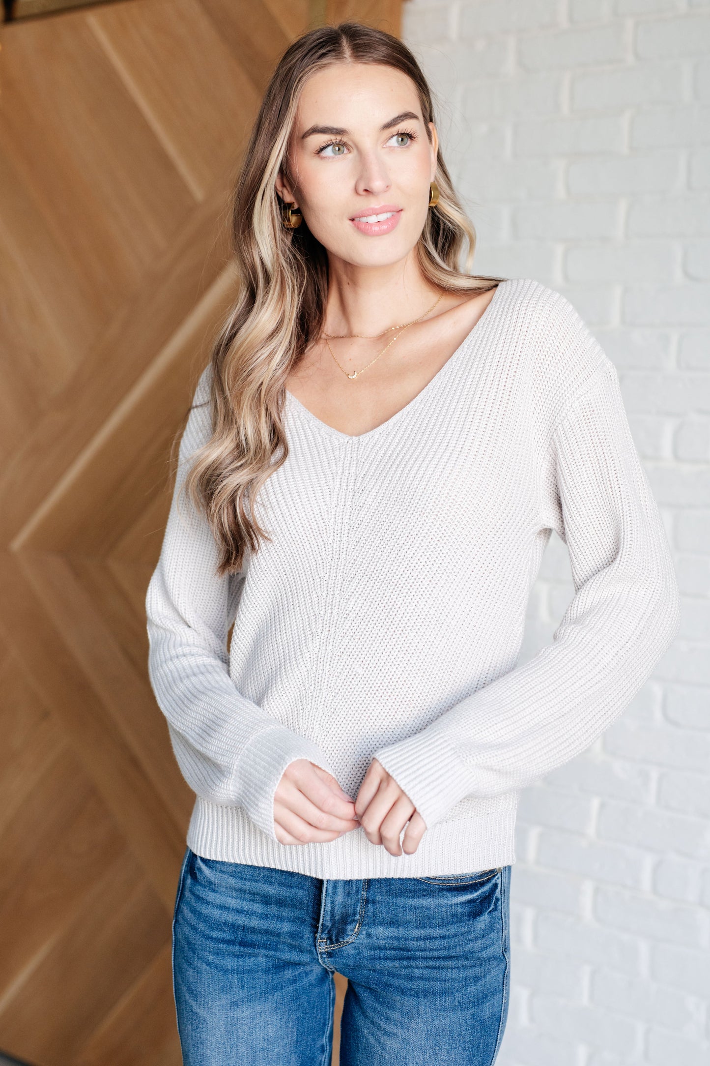 Model wearing Toula Ribbed Knit V Neck Sweater in cream with slim fit silhouette.