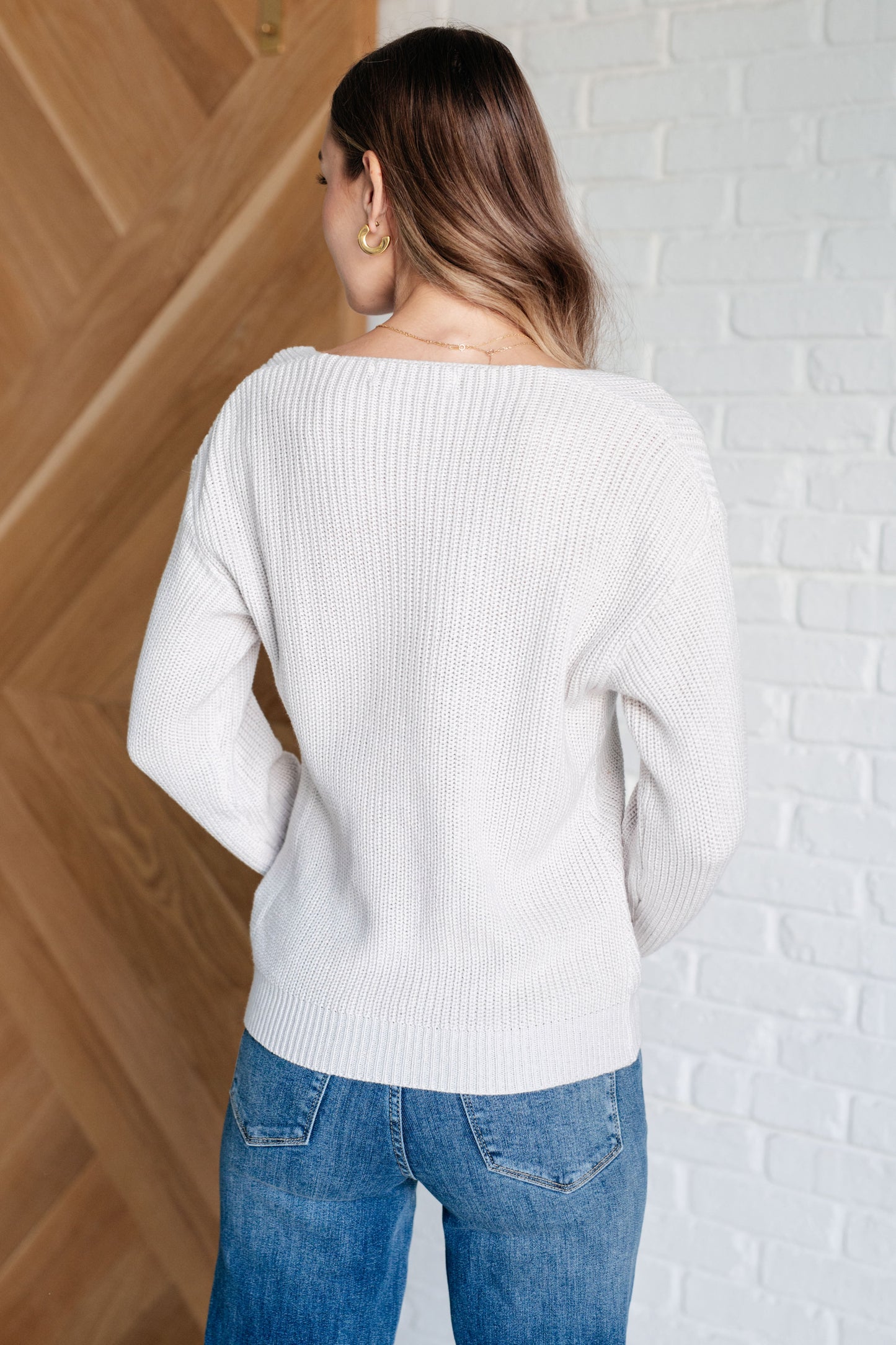 Women's light gray slim fit sweater with a V-neckline and long sleeves, made from lightweight sweater knit fabric.