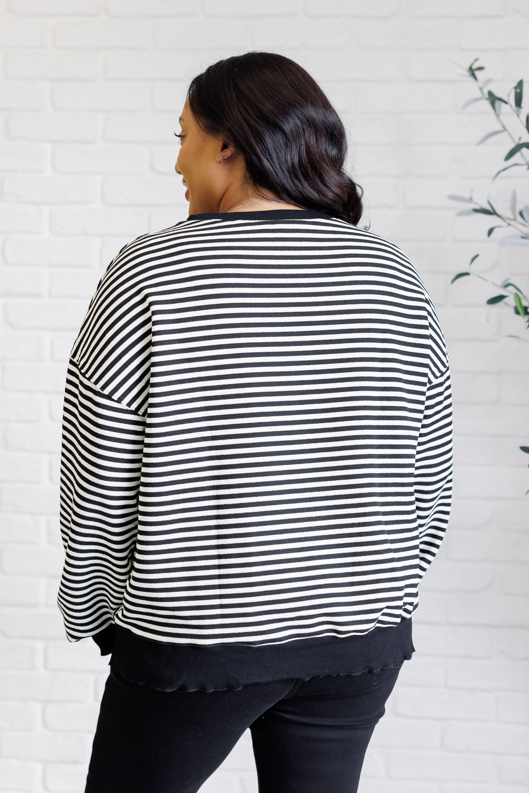 Women's black striped drop shoulder top with long sleeves, banded ribbed neckline, cuffs, and hemline, made of midweight knit fabric.