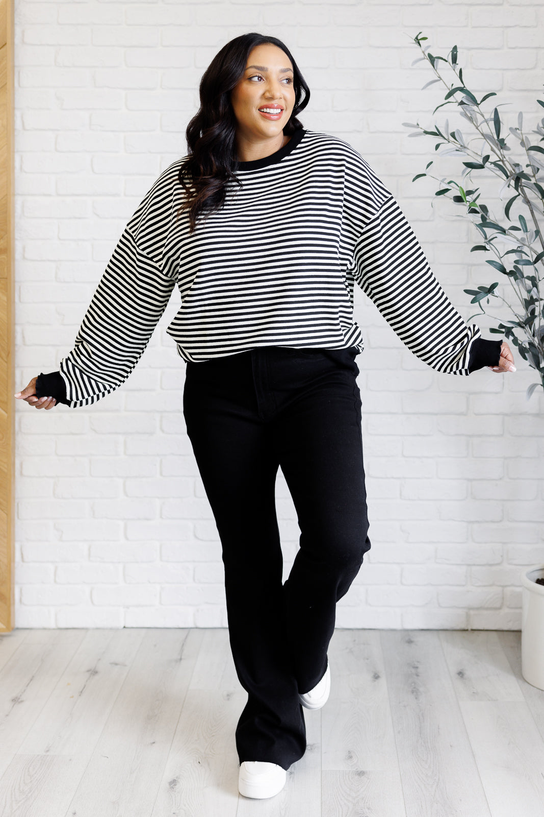 Women's black striped drop shoulder top with long sleeves, banded ribbed neckline, cuffs, and hemline, made of midweight knit fabric.