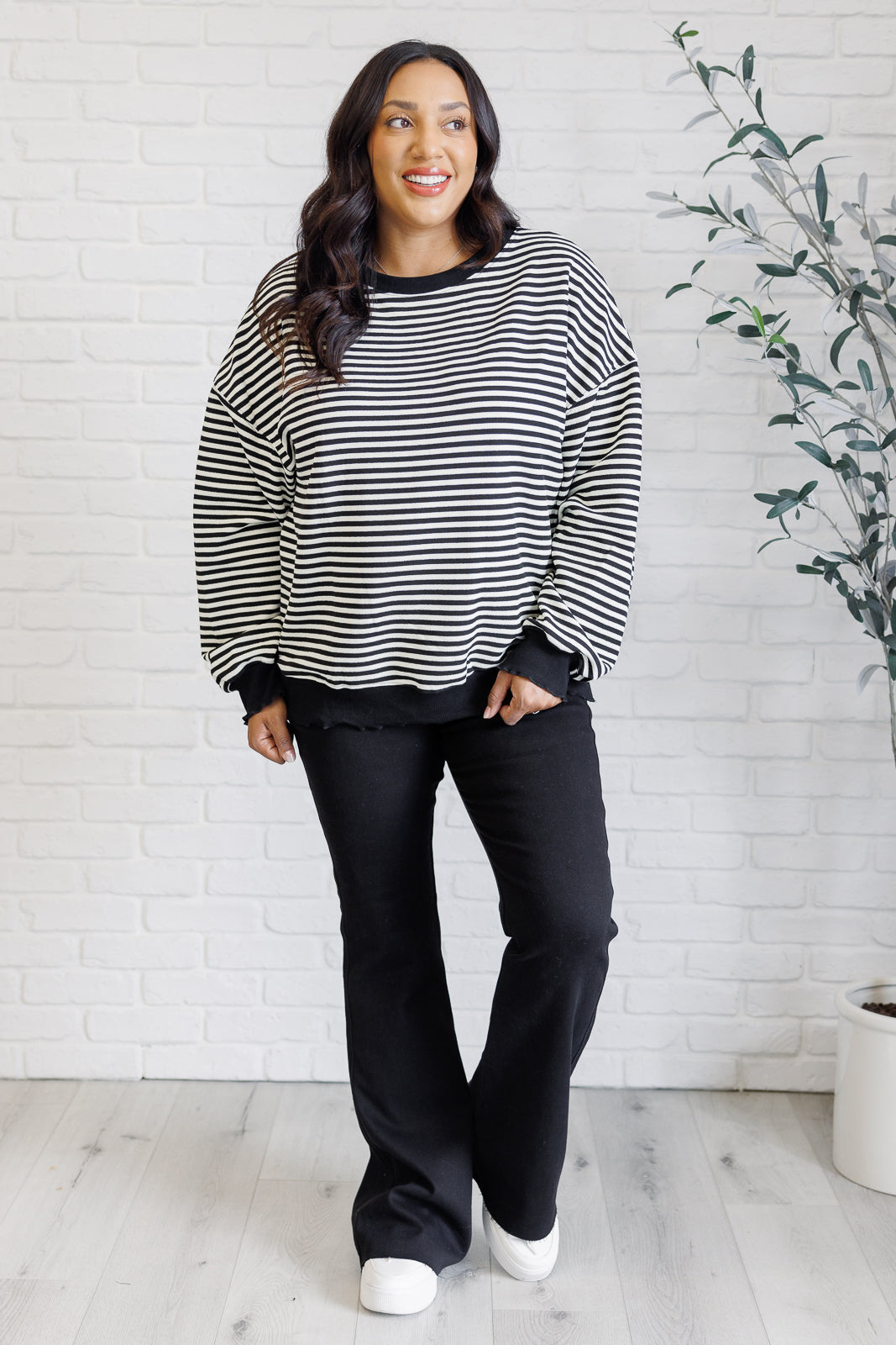 Women's black striped drop shoulder top with long sleeves, banded ribbed neckline, cuffs, and hemline, made of midweight knit fabric.