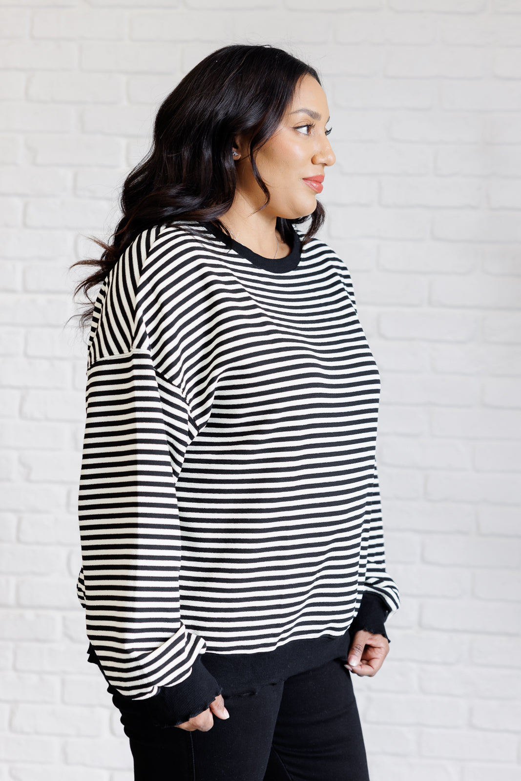 Women's black striped drop shoulder top with long sleeves, banded ribbed neckline, cuffs, and hemline, made of midweight knit fabric.