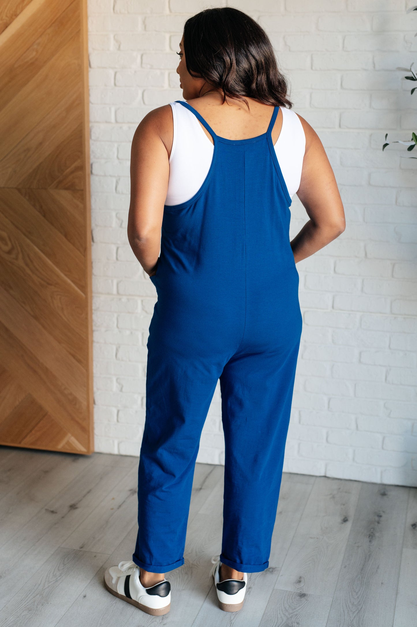 Light Navy spaghetti strap jumpsuit with a scooped neckline, patch pockets, and tacked cuffs at the hem.