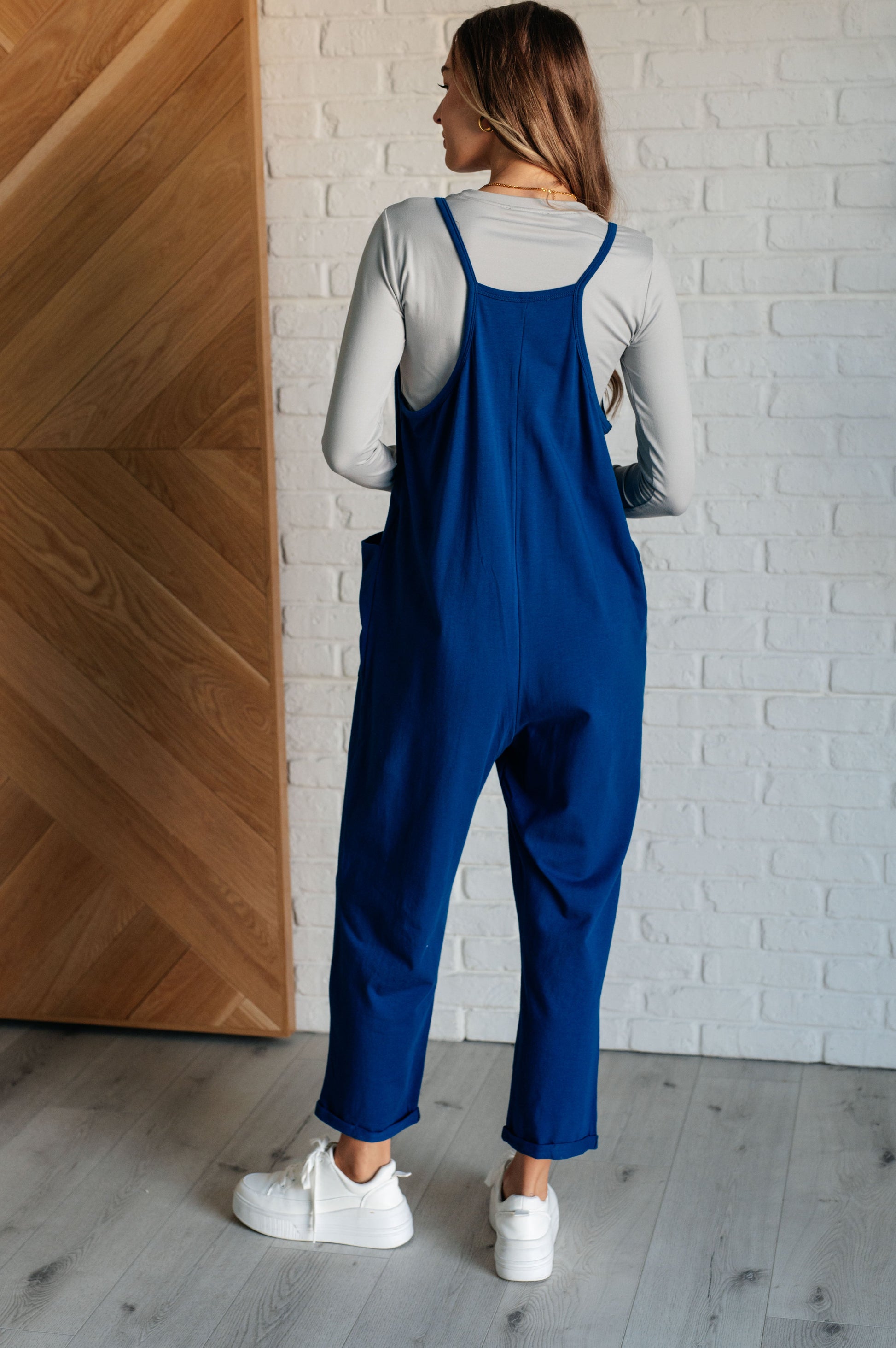 Light Navy spaghetti strap jumpsuit with a scooped neckline, patch pockets, and tacked cuffs at the hem.