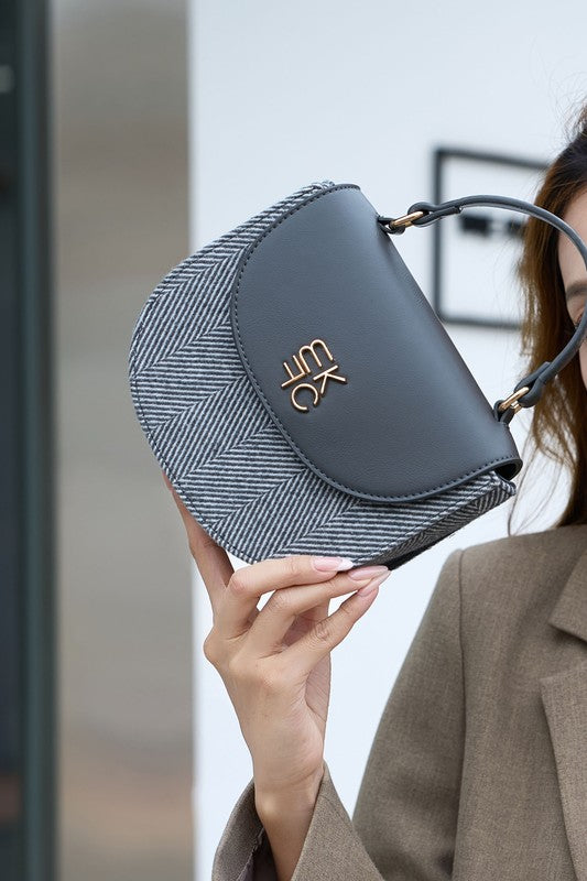 Woman holding gray Heloise herringbone crossbody bag showing size and handle.