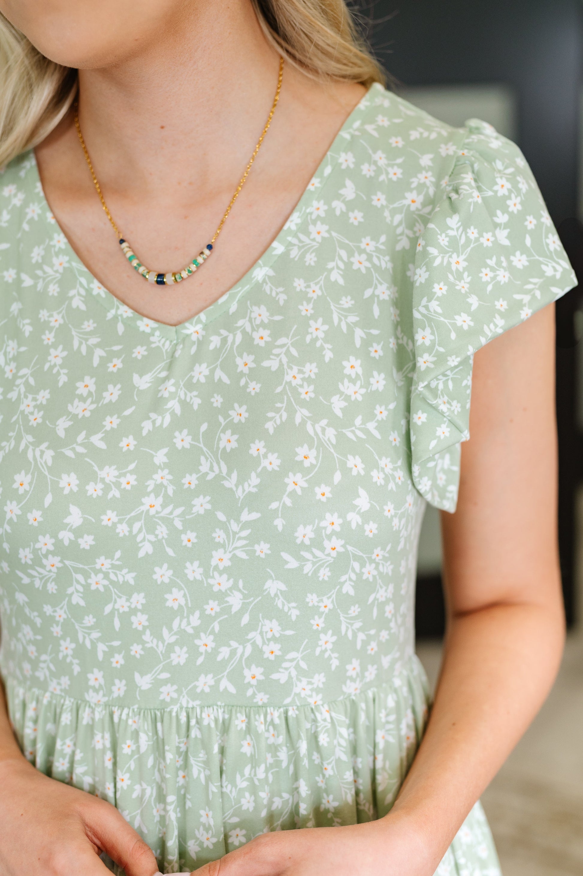 Close-up of the Lakelynn Flutter Sleeve Dress in sage highlighting the double-layered flutter sleeve, V-neckline, and subtle floral pattern in the brushed knit fabric.