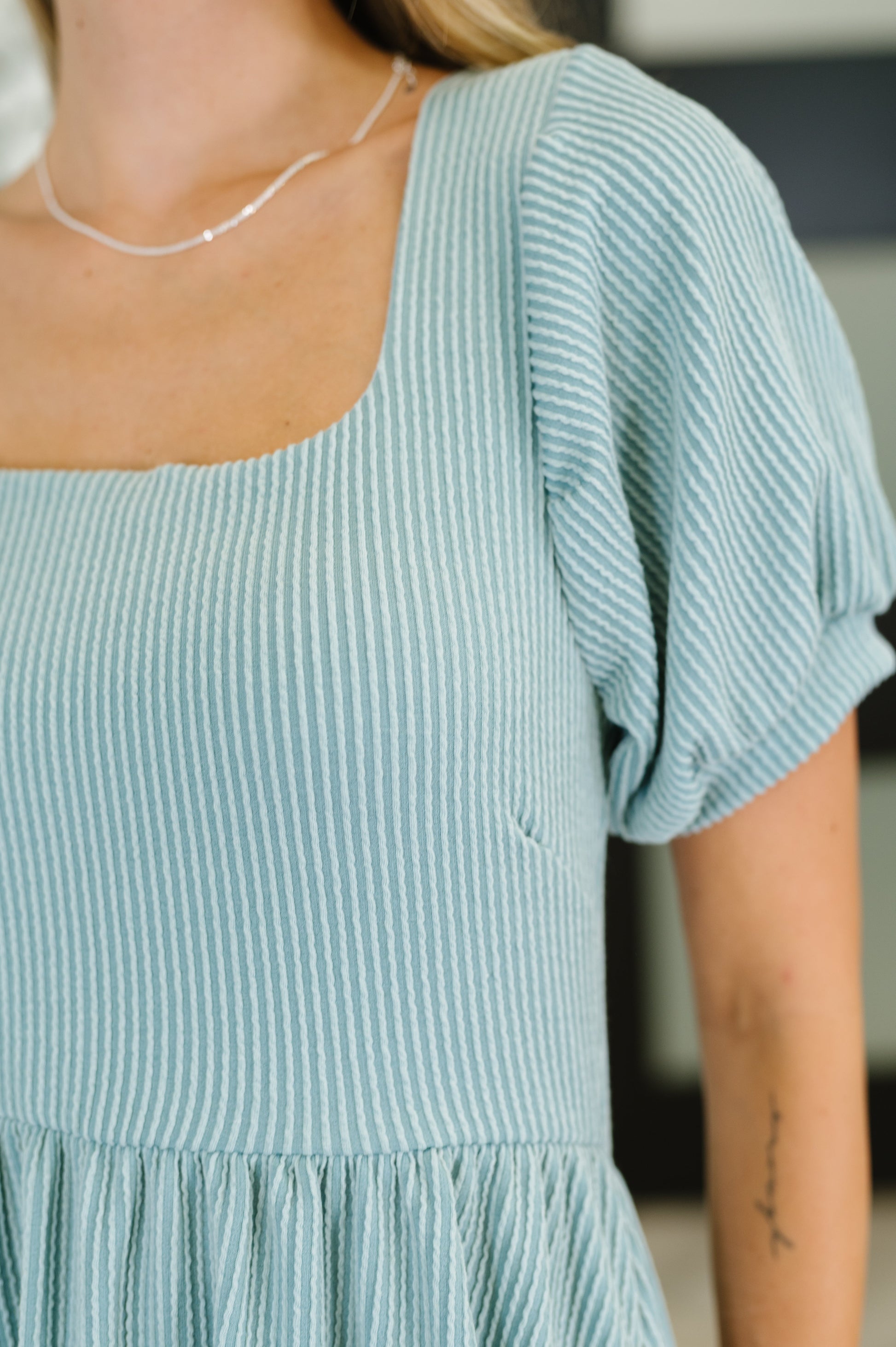 Close-up of Genevieve knit dress showing balloon sleeve cuff and square neckline ribbed detail.