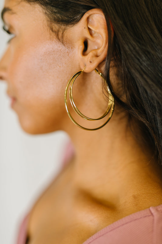 Close-up of a person wearing the Two's a Party - gold double hoop earrings with hinge closure.