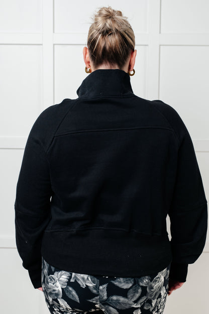 Plus size model back view of Sara Half Zip Pullover in black with ribbed hemline.