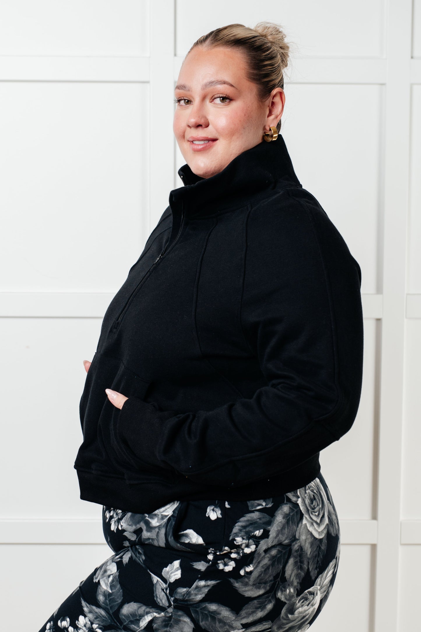 A women's pullover made from soft black terry cloth, featuring a high neckline with a half-zip closure, raglan long sleeves with thumbholes, banded ribbed cuffs and hem, and a kangaroo pocket.