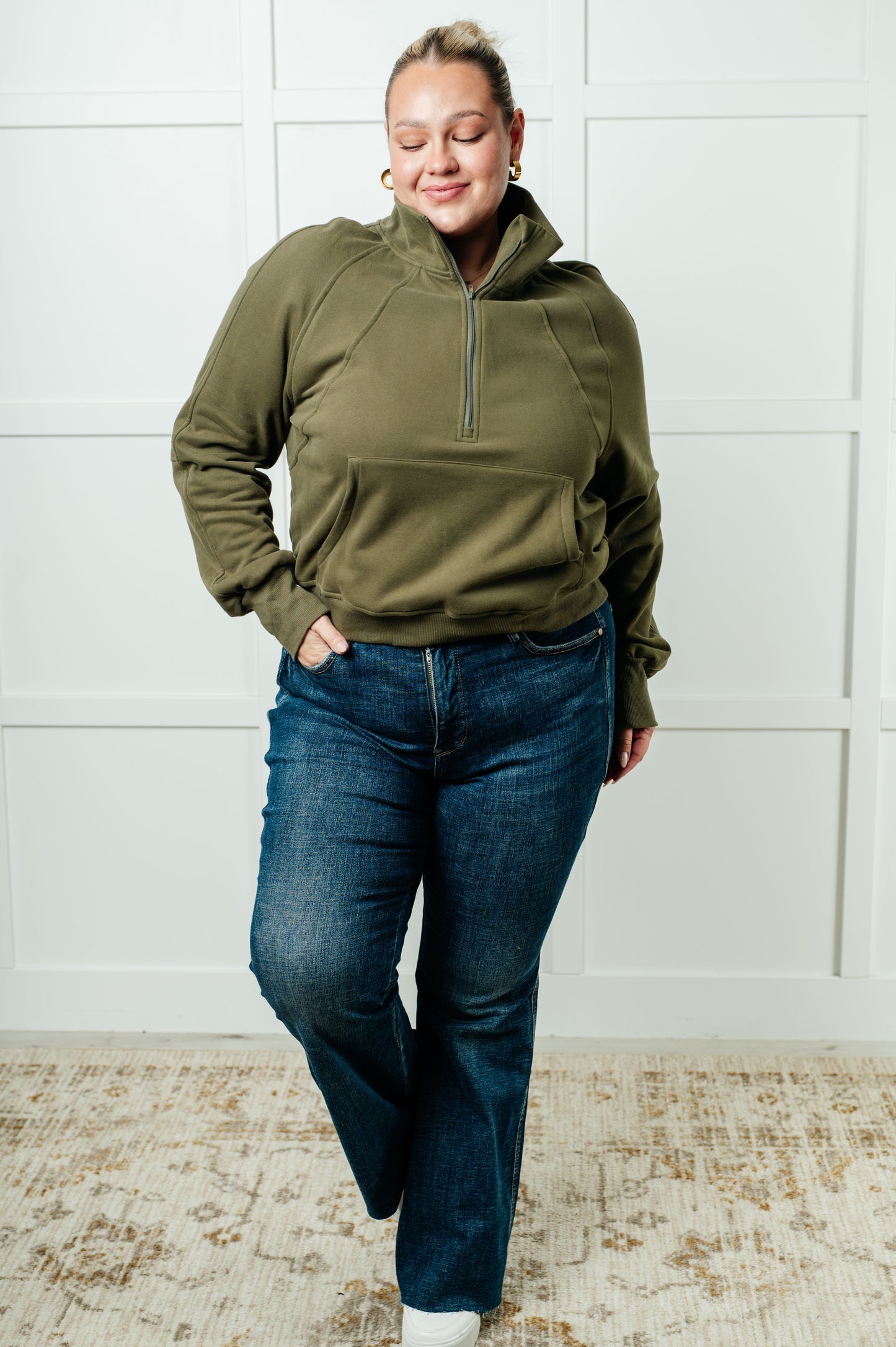 A women's pullover made from soft green terry cloth, featuring a high neckline with a half-zip closure, raglan long sleeves with thumbholes, banded ribbed cuffs and hem, and a kangaroo pocket.