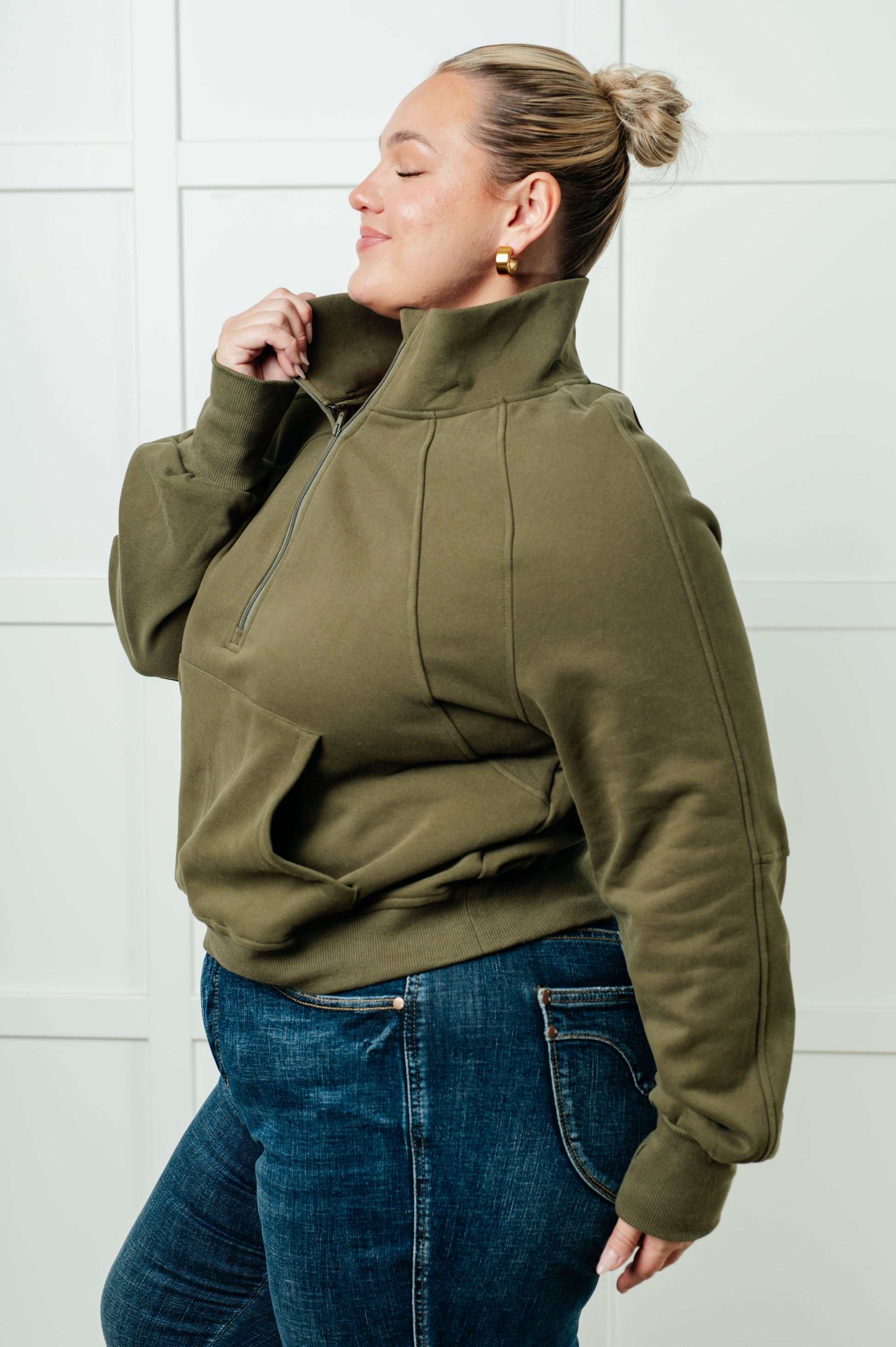 A women's pullover made from soft green terry cloth, featuring a high neckline with a half-zip closure, raglan long sleeves with thumbholes, banded ribbed cuffs and hem, and a kangaroo pocket.