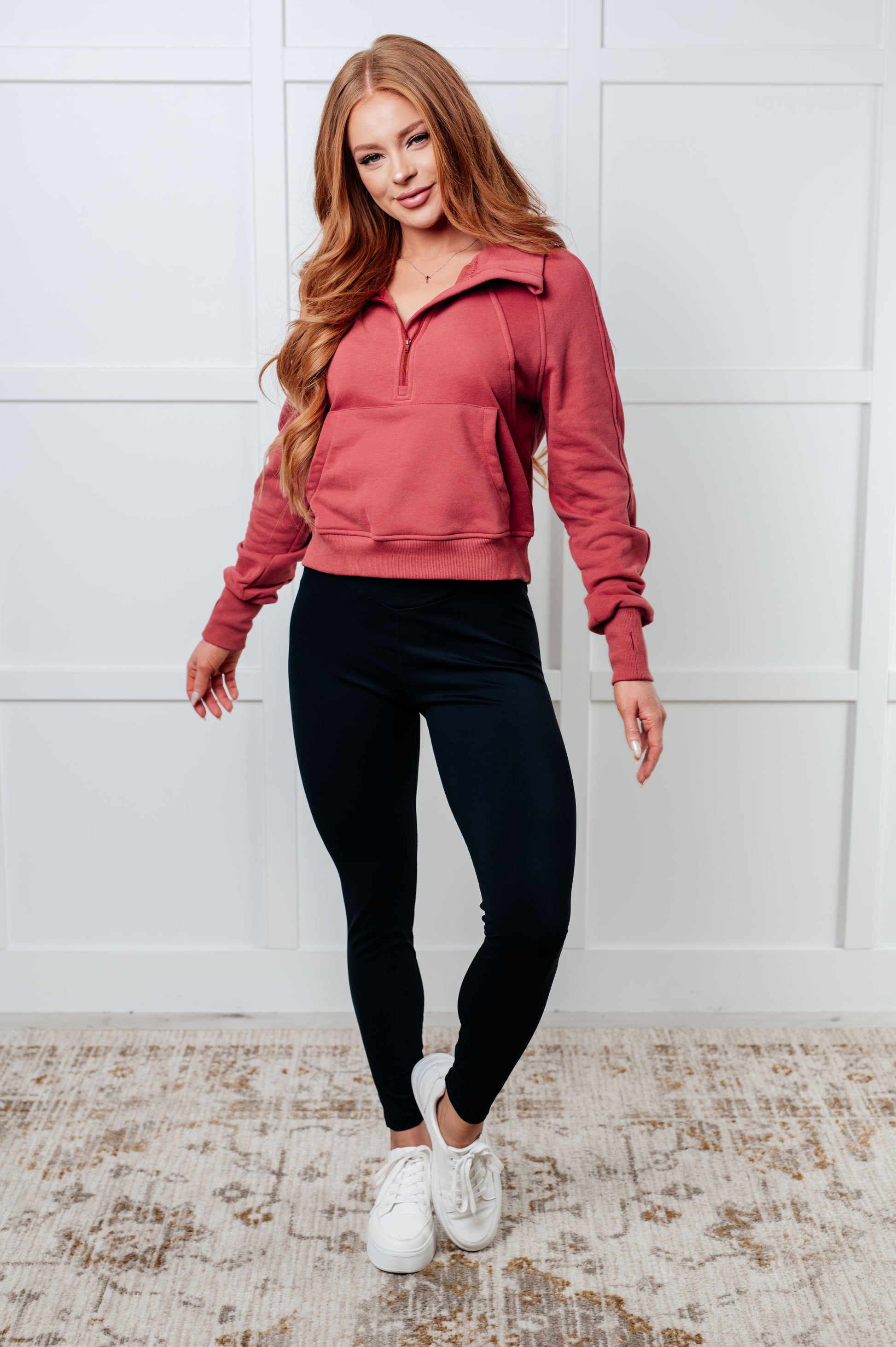 A women's pullover made from soft mauve terry cloth, featuring a high neckline with a half-zip closure, raglan long sleeves with thumbholes, banded ribbed cuffs and hem, and a kangaroo pocket.