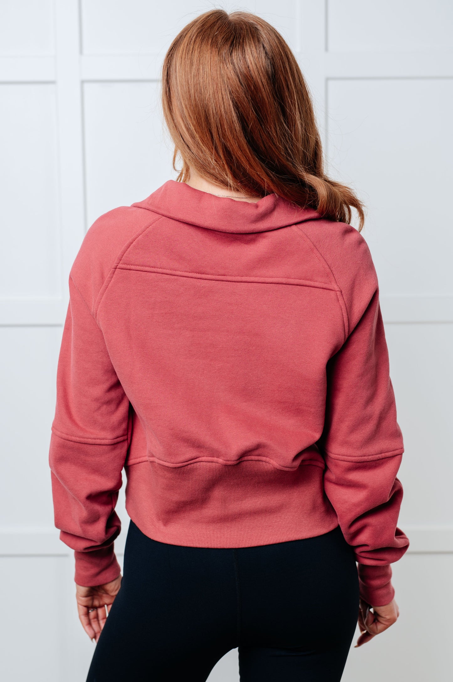 A women's pullover made from soft mauve terry cloth, featuring a high neckline with a half-zip closure, raglan long sleeves with thumbholes, banded ribbed cuffs and hem, and a kangaroo pocket.