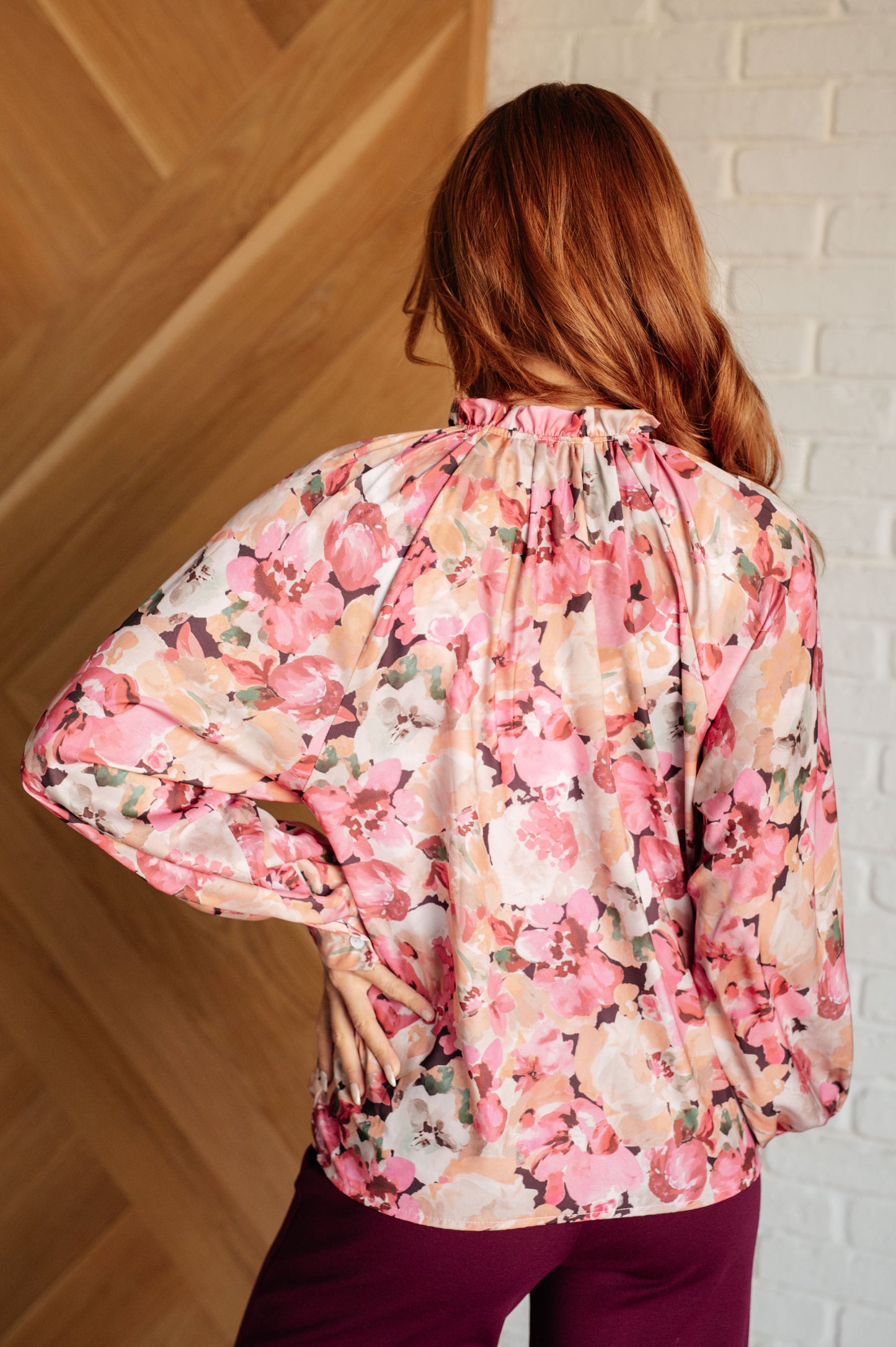 Women's pink floral blouse with poet sleeves, banded cuffs, ruffle details, and a high-low hem.