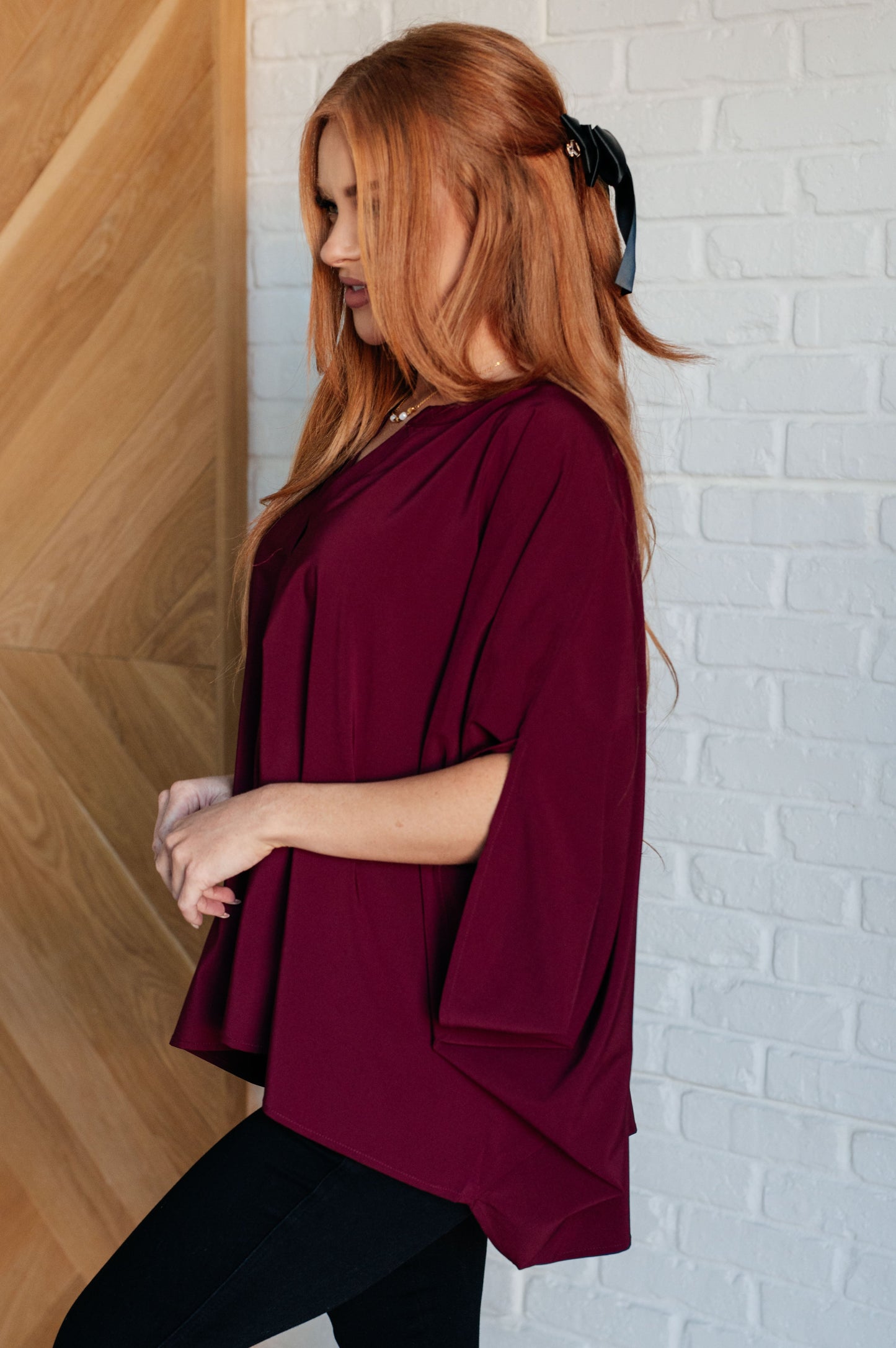 Women's wine-colored poncho-style blouse with a Gabby V-neckline, batwing sleeves, and an oversized fit, made from lightweight woven fabric.