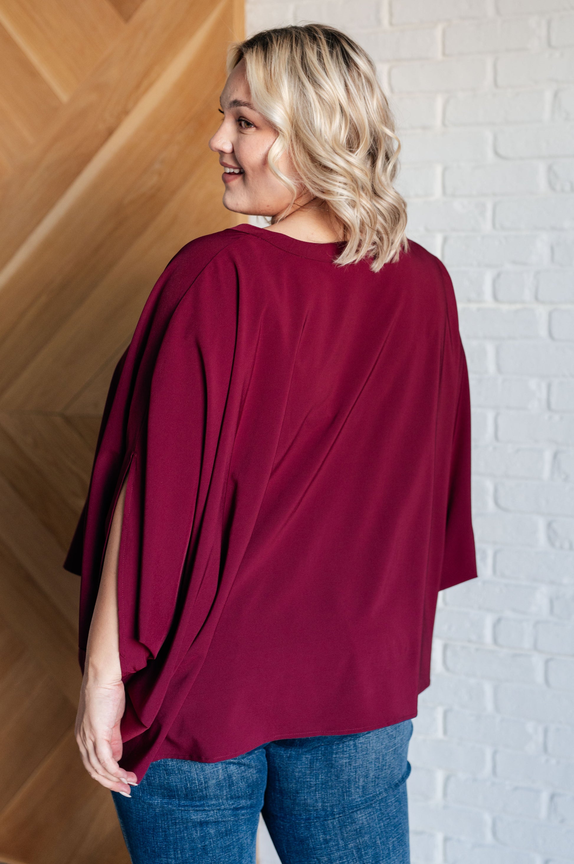 Women's wine-colored poncho-style blouse with a Gabby V-neckline, batwing sleeves, and an oversized fit, made from lightweight woven fabric.